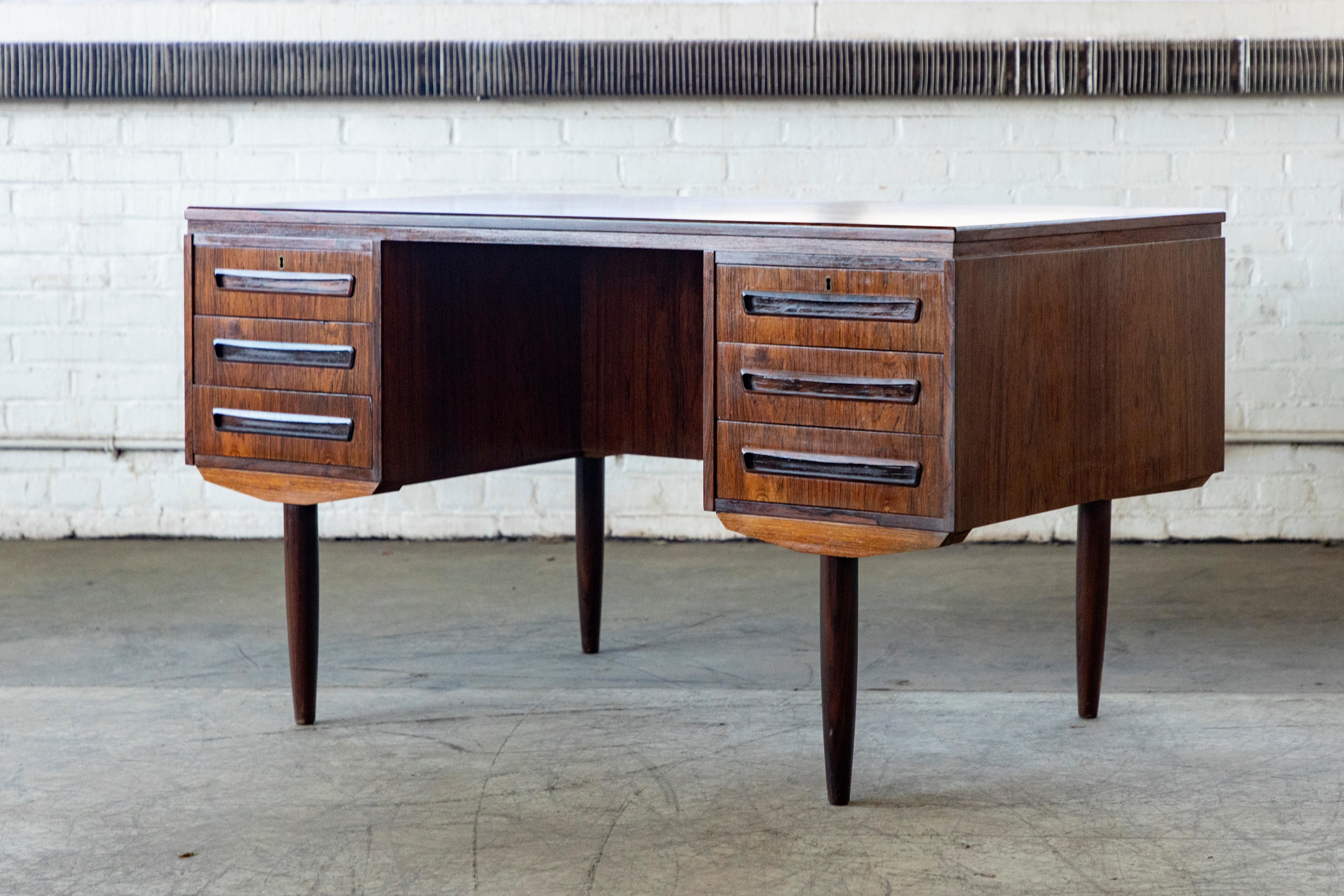 Beautiful Danish small executive desk in the style of ai Kristiansen and made of rosewood in Denmark sometime in the late 1950's or early 1960's by J. Svenstrup Mobler. This desk is slightly smaller than a traditional executive desk and fits well in