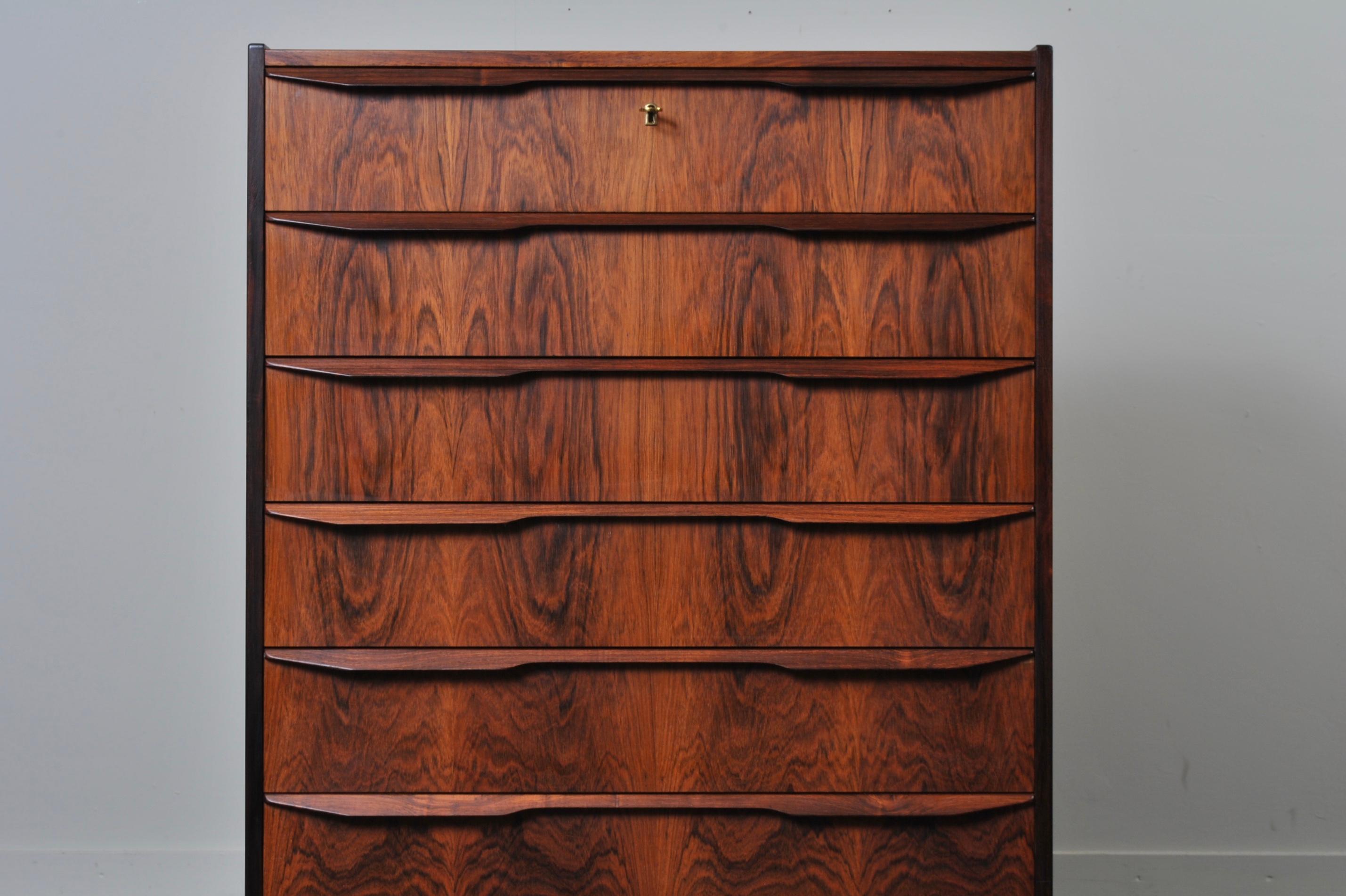 A Danish midcentury rosewood tallboy chest of drawers. Produced in Denmark, circa 1960. Lockable top drawer. Lipped handles. All drawer interiors are clean and in good condition throughout. Beautifully matched rosewood veneer frontage.
