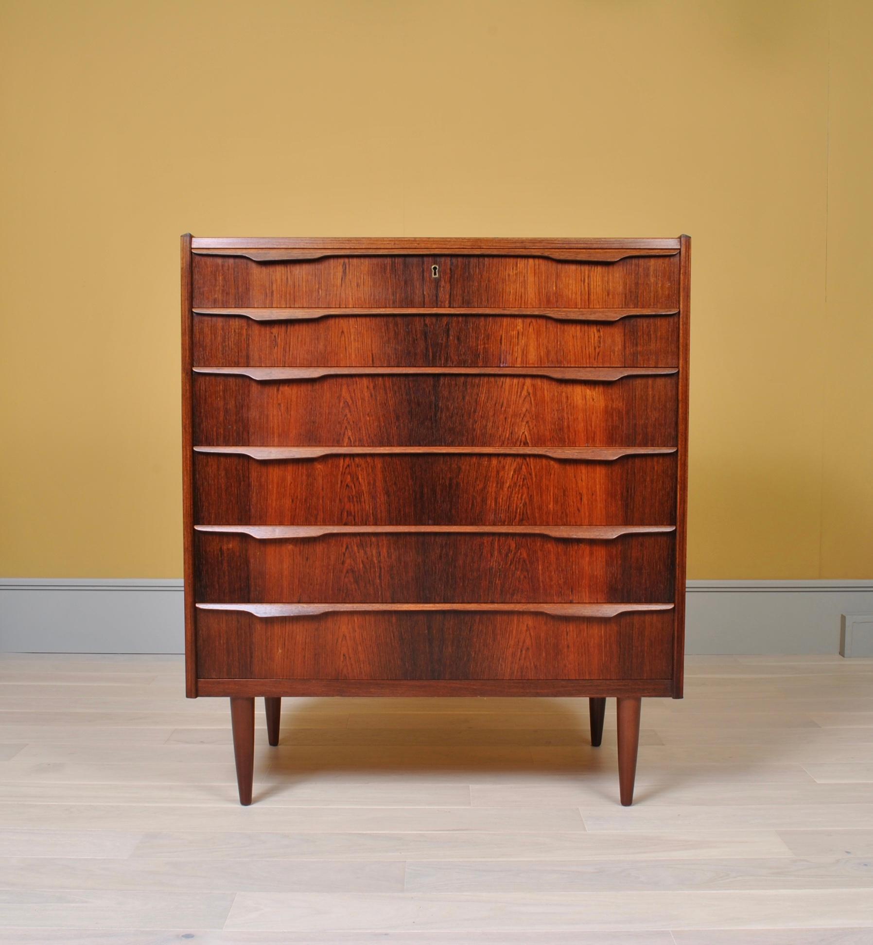 A classic Danish midcentury rosewood tallboy chest of drawers. Produced in Denmark circa 1960. Nice sleek profiled hand pulls. 