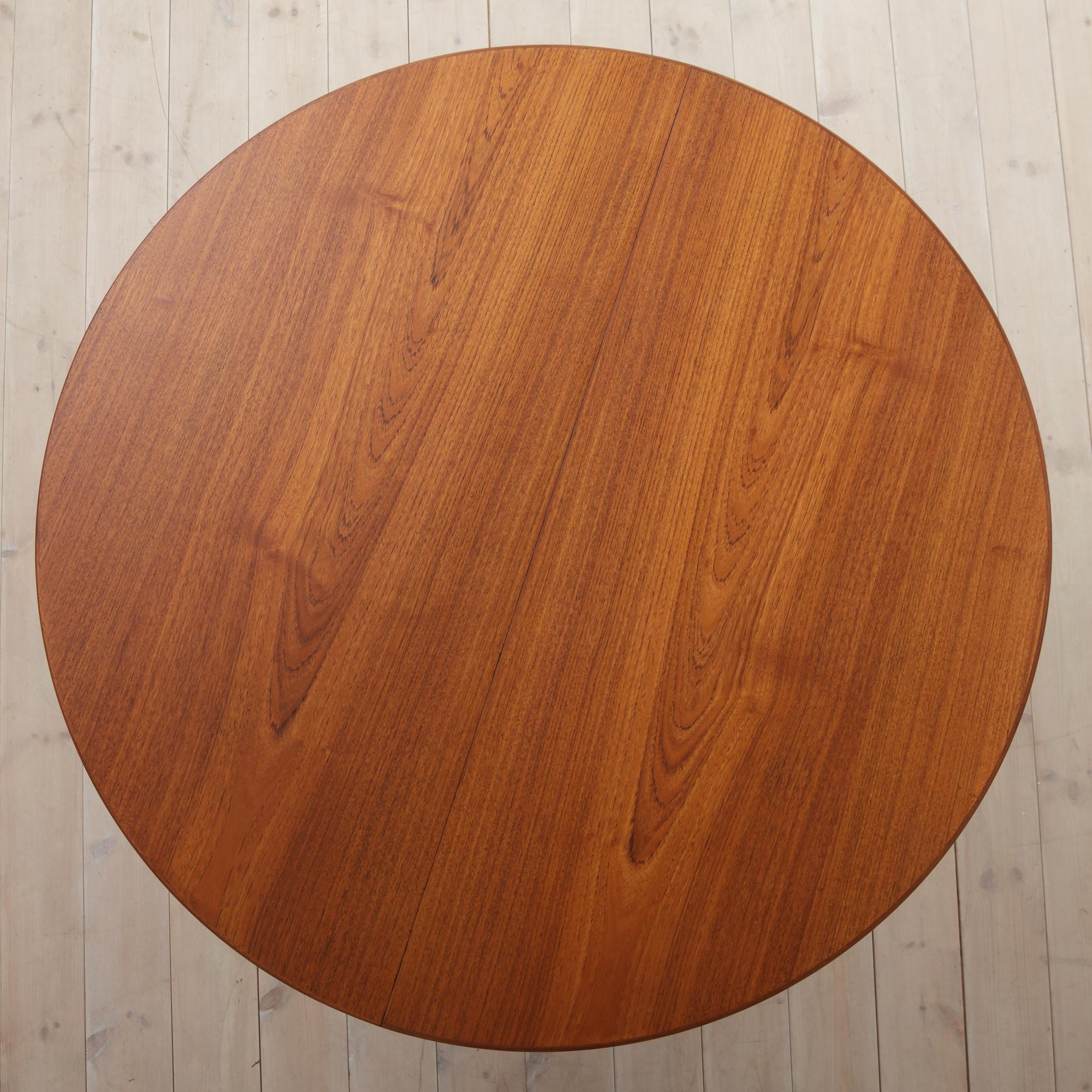 Minimalist Danish round table with wonderful triangular solid teak legs, metal runners, and two extension leaves. The diameter is 110cm, extensions are 50cm wide each, one with an apron. The runners have stopping mechanism, that prevents it from