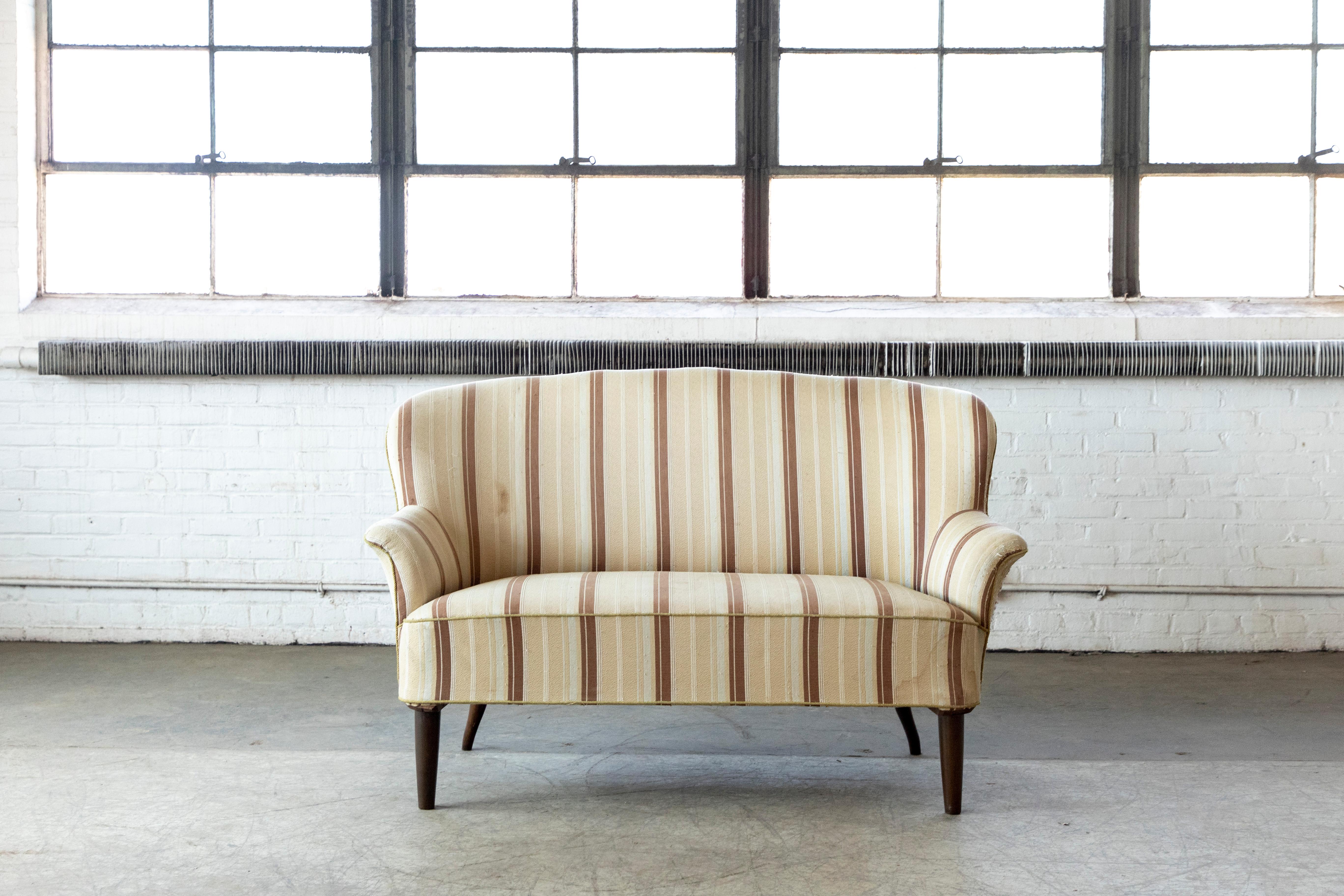 Elegant Danish or Swedish settee or loveseat from circa 1950s in the style of Carl Malmsten. We found this charming settee near Copenhagen but it has clear Swedish design cues namely the roll on the armrest and the high backrest but even more so the