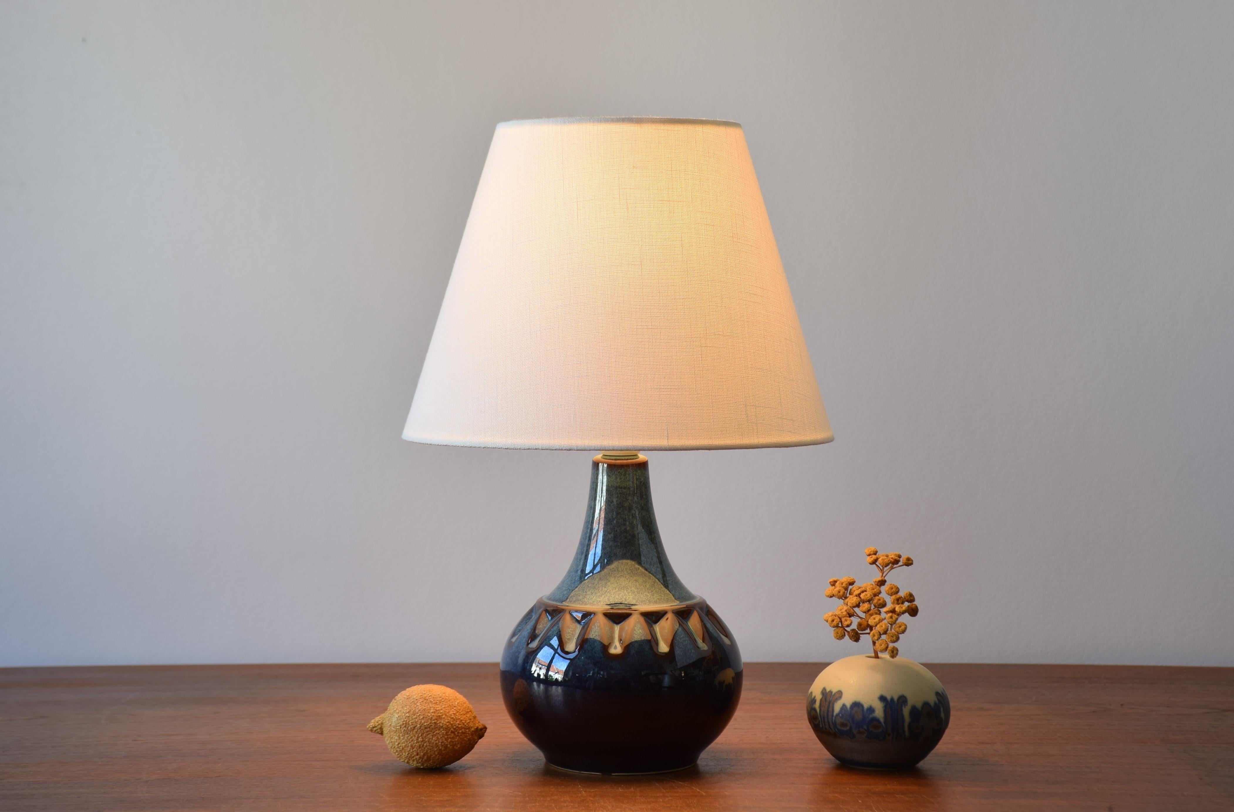 Midcentury Danish small table lamp by Søholm Stentøj, Denmark. Made circa 1960s.
The lamp has a shiny blue glaze with brown elements on the repeated decor around the shoulders of the body. 

Included is a new lamp shade designed in Denmark. It is