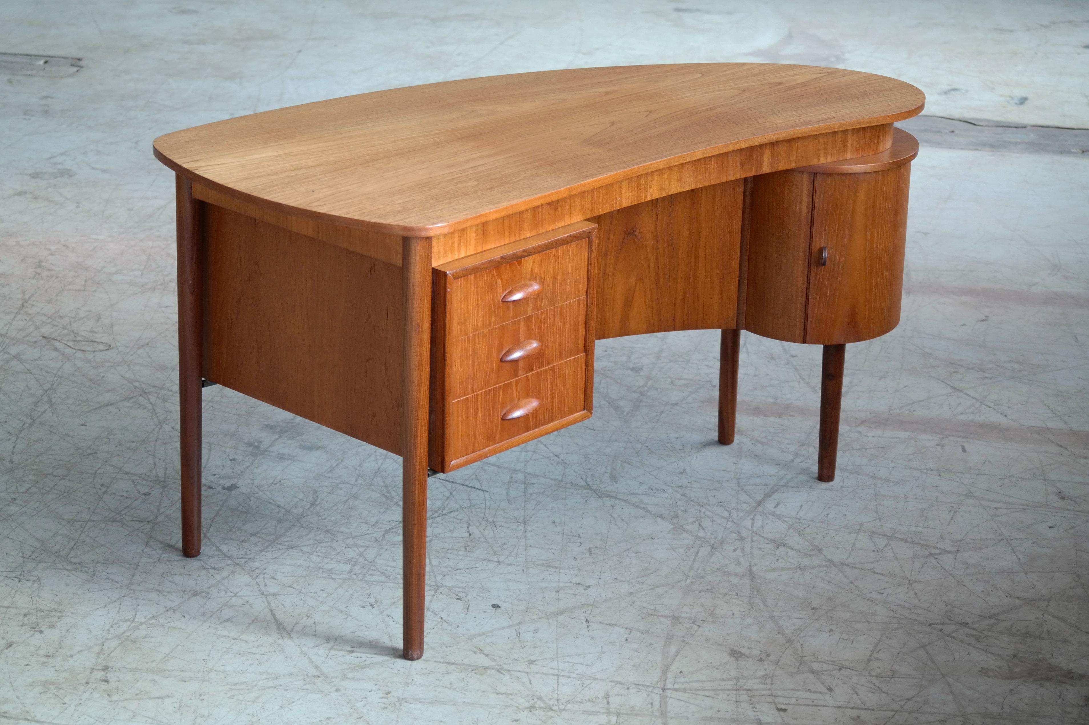 Beautiful Danish small executive desk in teak in the style Kai Kristiansen and made in Denmark in the early 1960s. Has the characteristic Kai Kristiansen very organic kidney-shaped design of the top and hand carved pulls. Due to its size it's very
