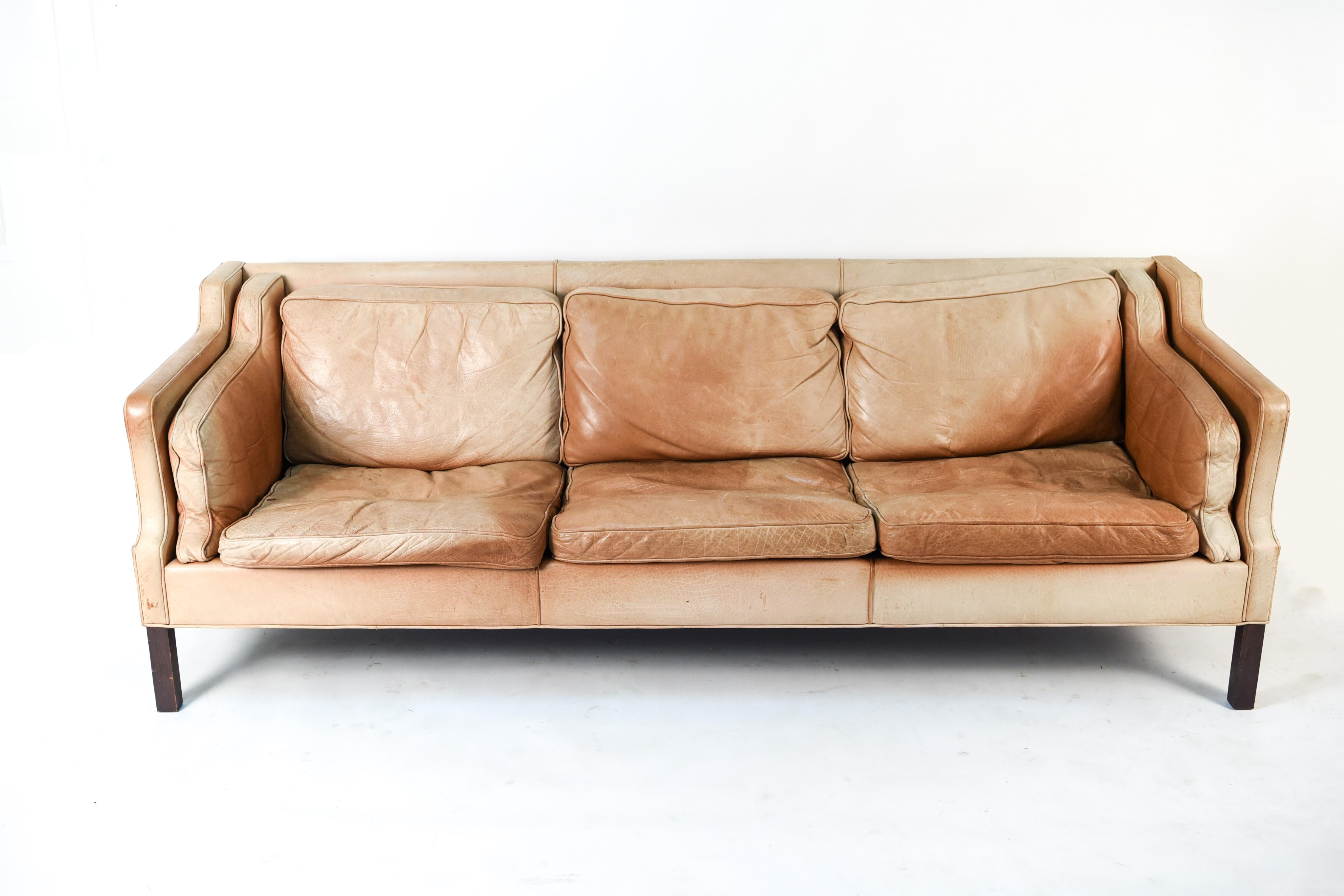 This Danish midcentury three-seat sofa is by designer Rud Thygesen. This sofa is typical of the Classic Scandinavian designs of the 1960s and retains its timeless desirability. Upholstered in vintage leather, this sofa has a wonderful patina