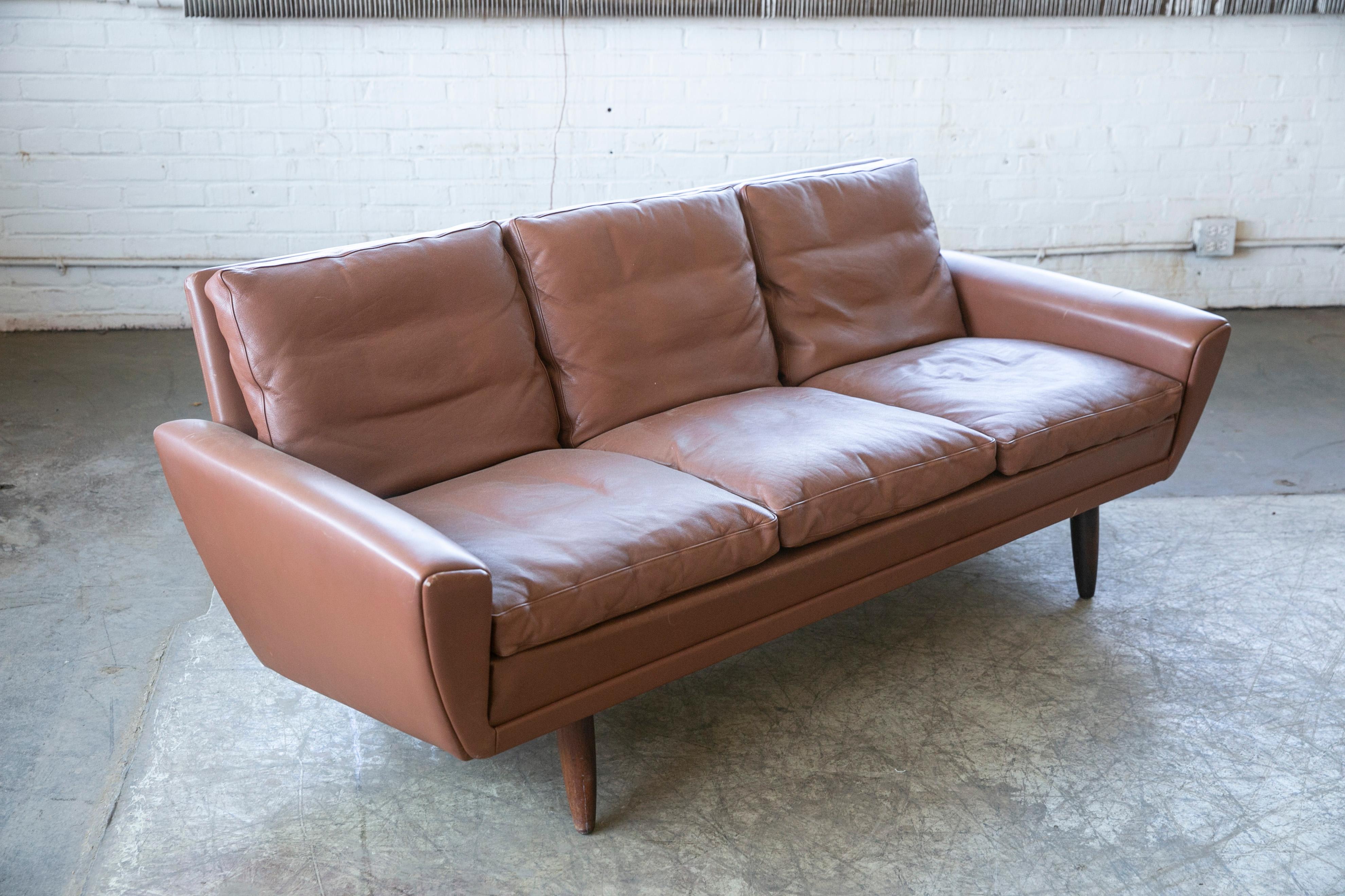 Classic Danish 1960s designed sofa by Kurt Ostervig in a nice cognac brown leather and probably produced by either Ryesberg or Rolschau Mobler of Denmark both of which produced furniture for Designer, Kurt Ostervig. Down filled cushions for that