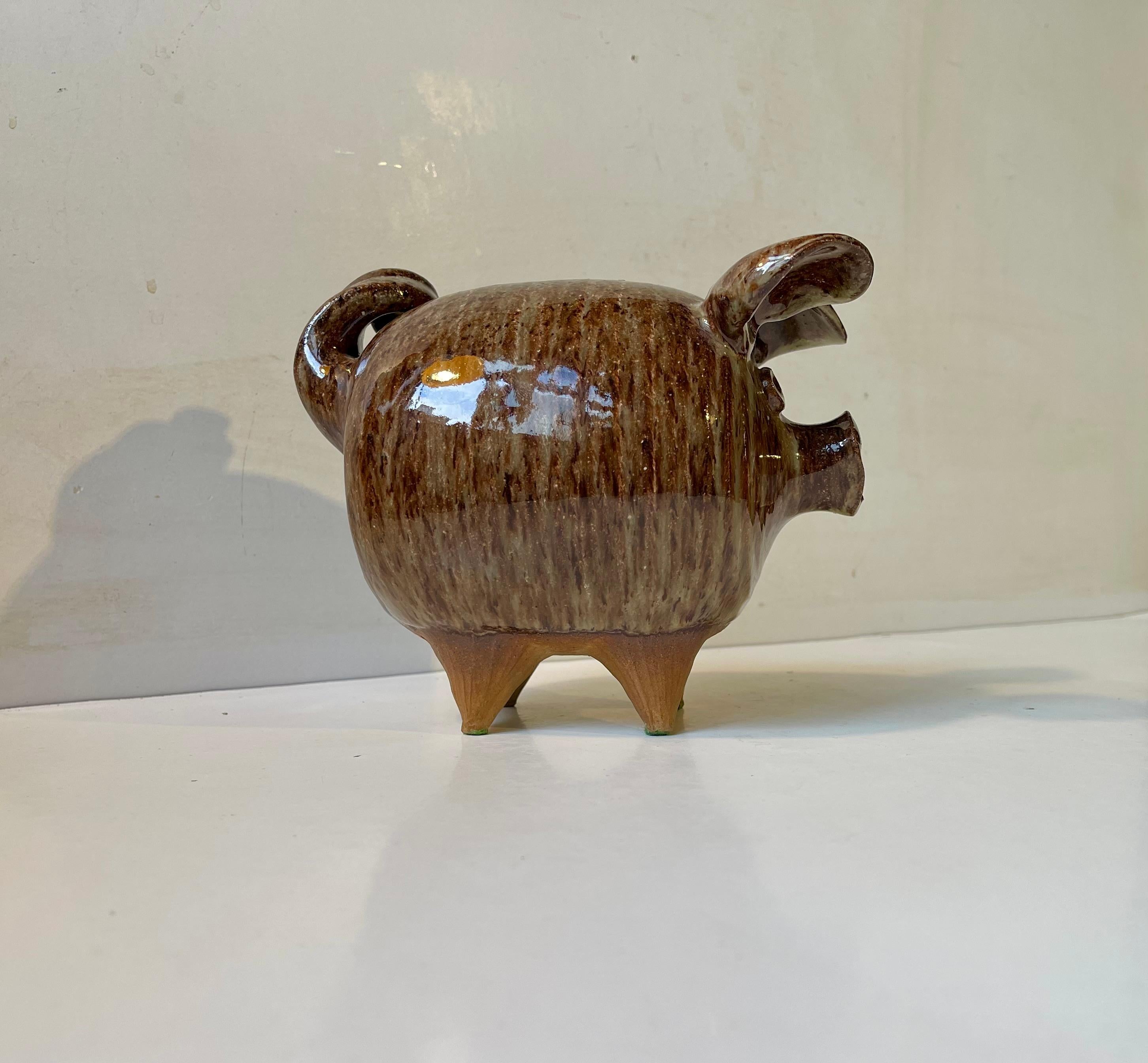 A chubby and unusual Money bank pig executed in glazed studio stoneware. A unique design by the Danish ceramist Per Steffen Petersen who from the 1940s onwards worked at Kähler in Denmark. He opened his own workshop in 1970 where this cutie was