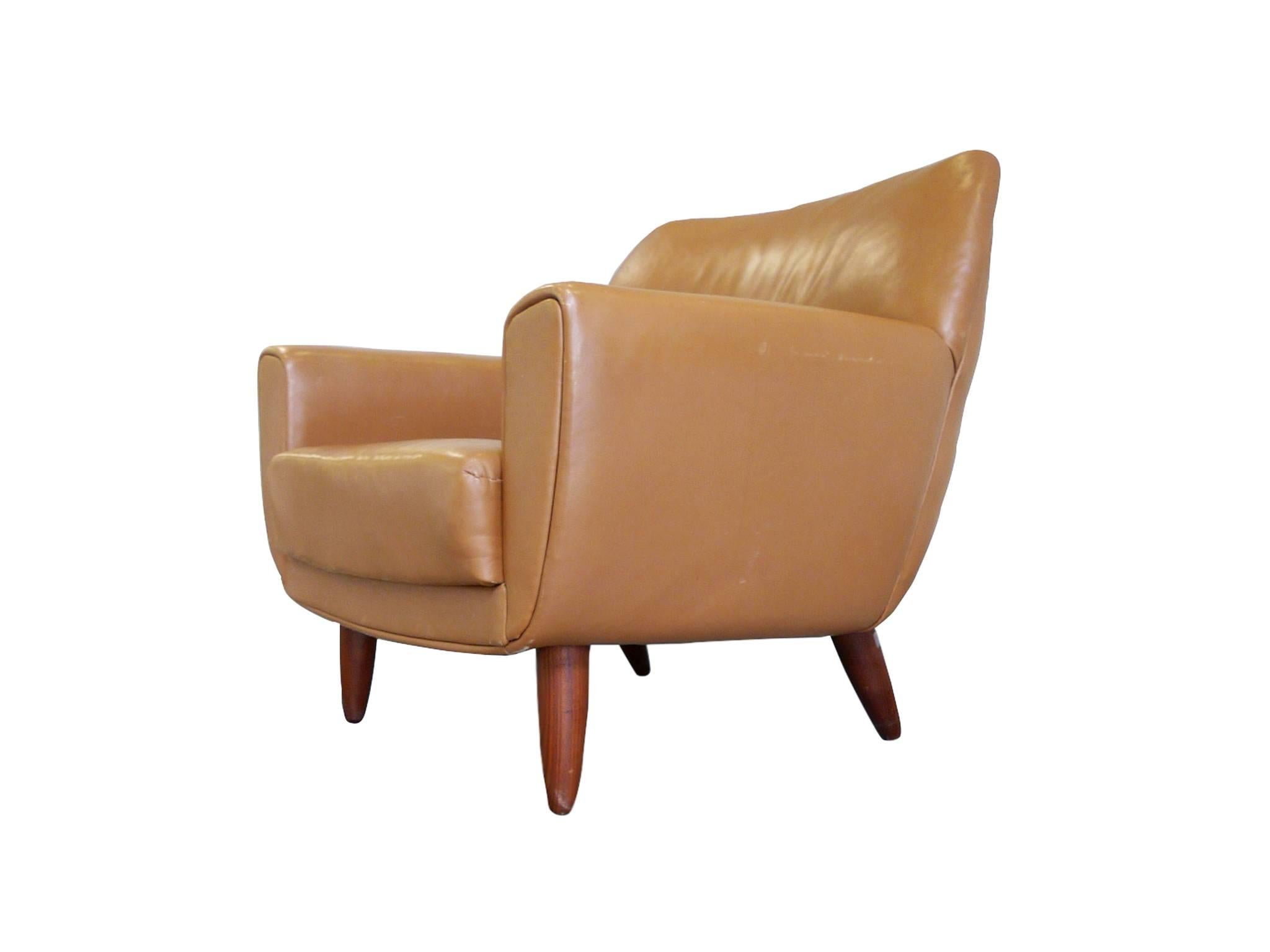This handsome tan lounge chair was designed by the Danish designer Illum Wikkelsø in the mid-20th century. It is a rare find. The chair is comprised of teak frame and legs and leather upholstery. Like many of his furniture designs, this chair