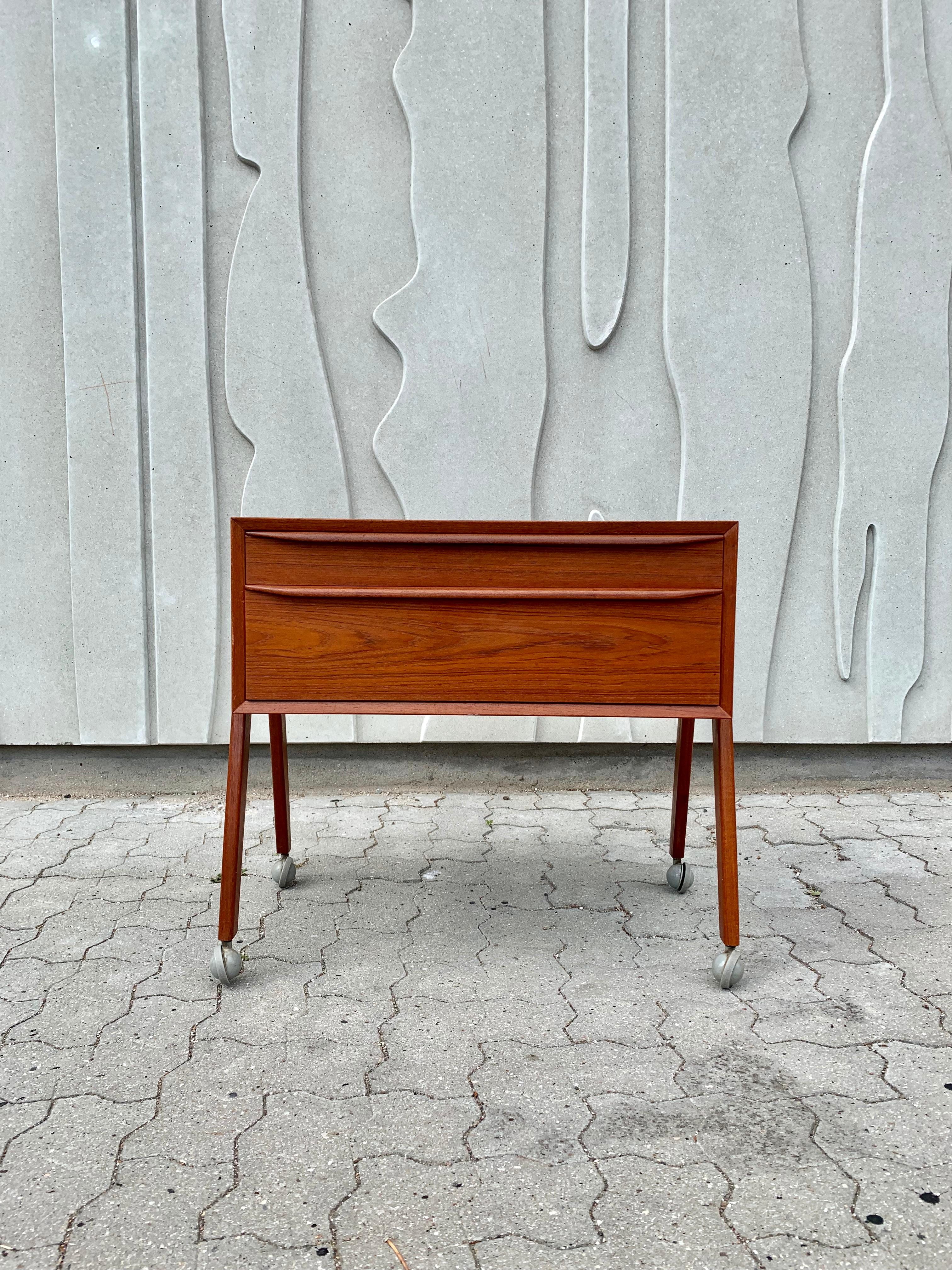 Stunning cabinet designed and manufactured in Denmark. Featuring two drawers and a base made of solid teak, stands on castors. In the style of Arne Vodder.