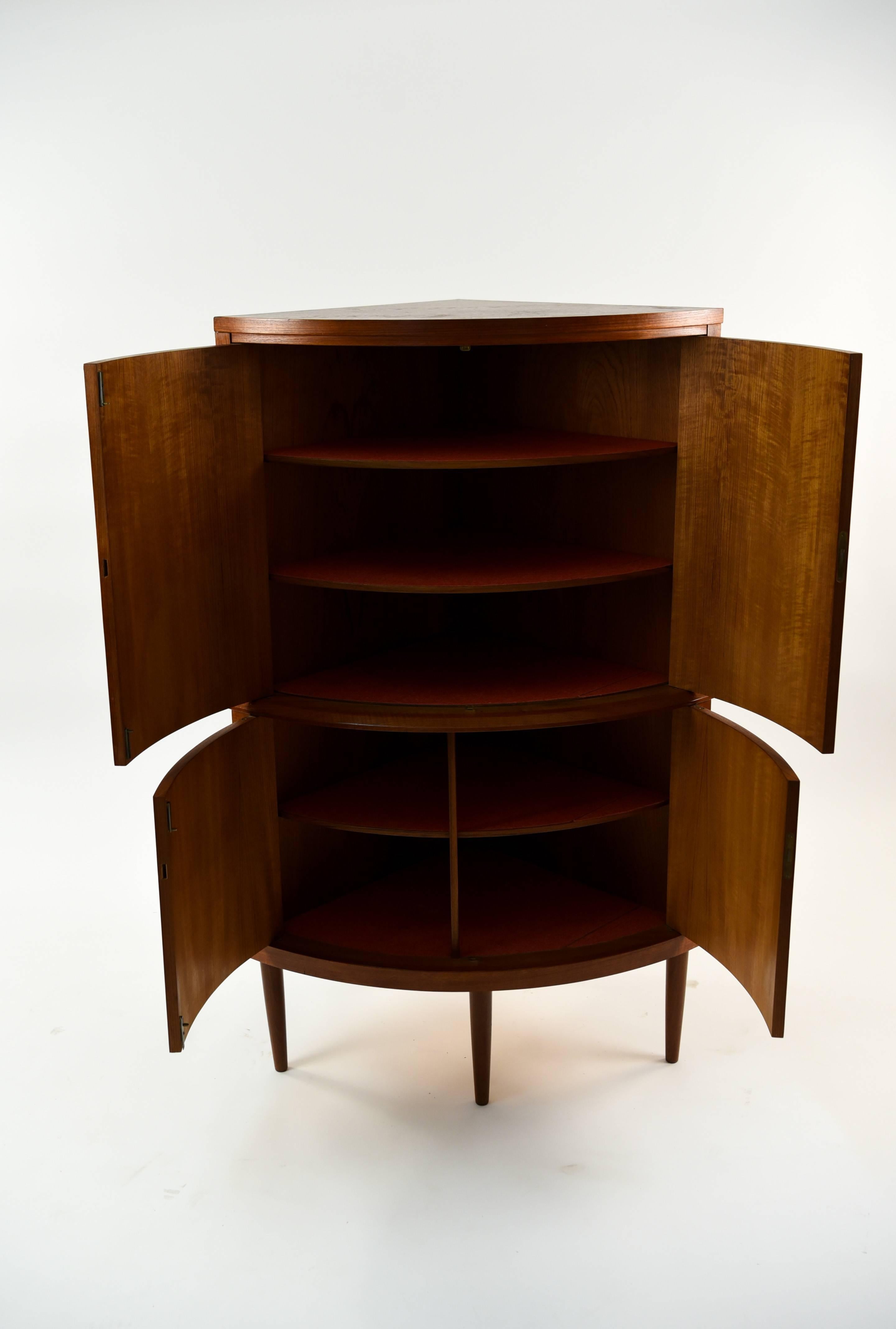 This Danish midcentury cabinet is made of teak wood. The beauty of the corner cabinet is its ability to remain tucked away without intruding into the space of a room. This cabinet provides a good storage area and great midcentury design that make it