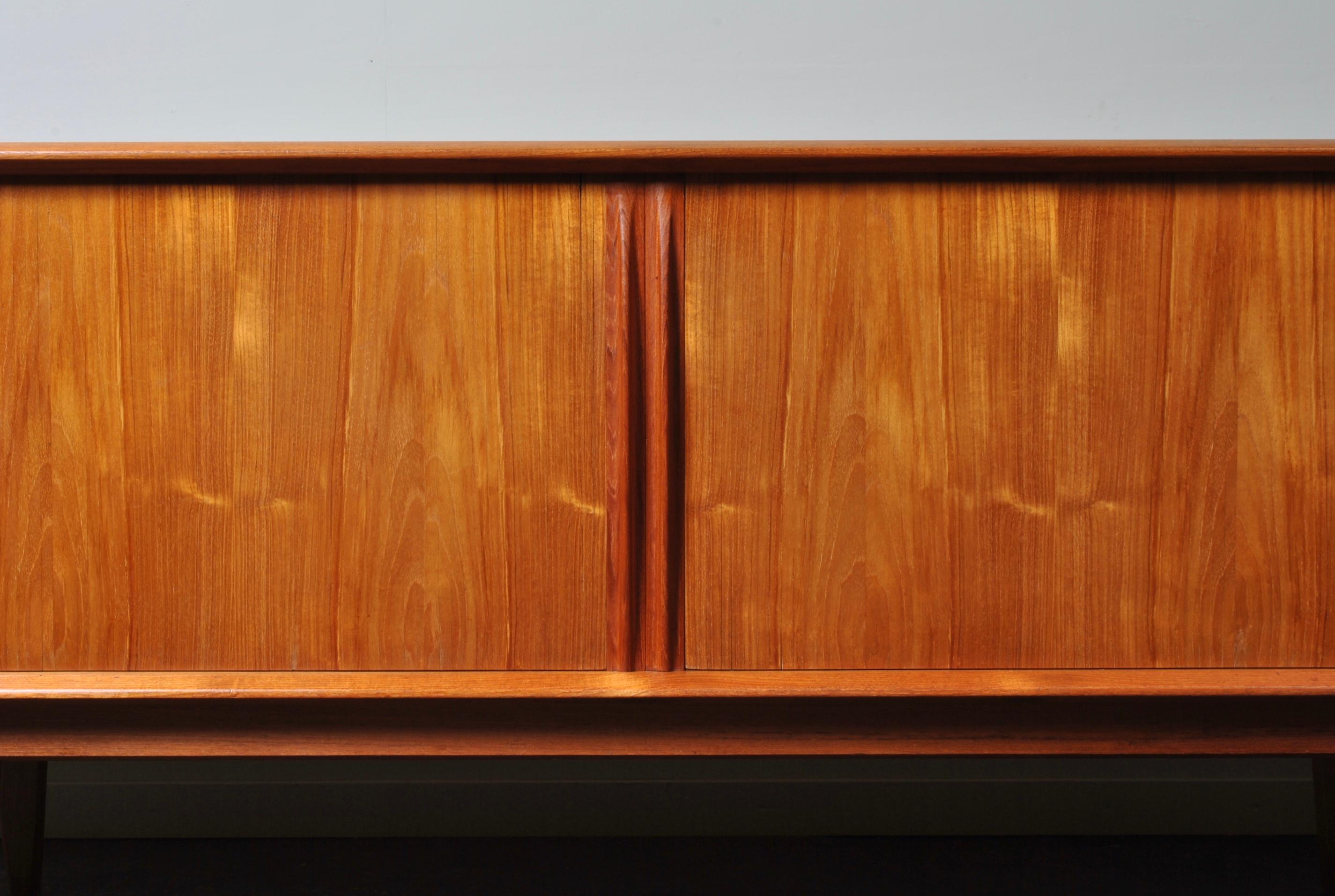 Large Danish midcentury teak sideboard or credenza. Tambour door front with 4 internal central drawers and adjustable shelves either side. Produced in Denmark circa 1960 by Bernhard Pedersen.
Wonderfully simple modernist design. Smooth sliding