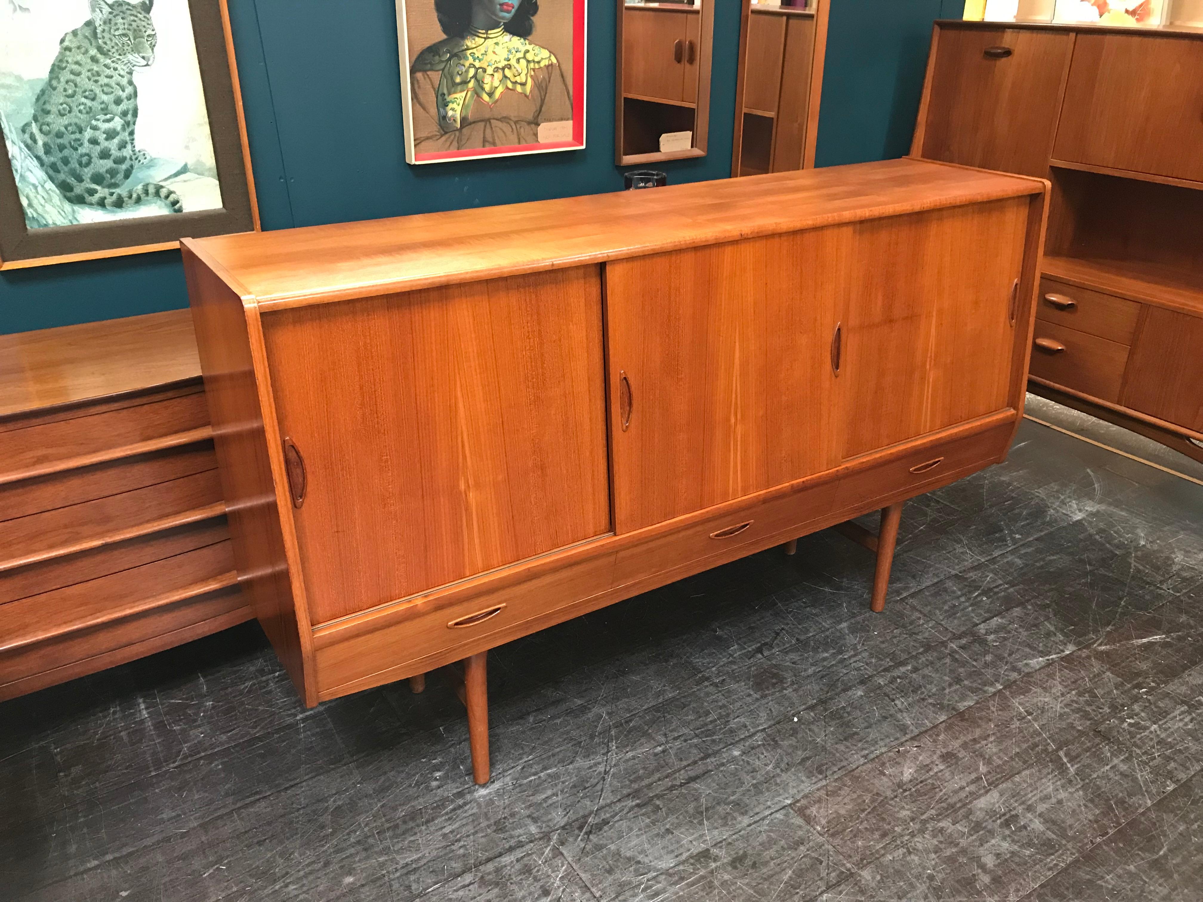 A stunning Danish sideboard in teak, manufactured by Aerthoj Jensen & Molholm of Herning, Denmark in the 1960s. Consists of 3 sliding doors above 3 drawers, all with beautifully shaped handles. The area behind the middle door can be used as a drinks
