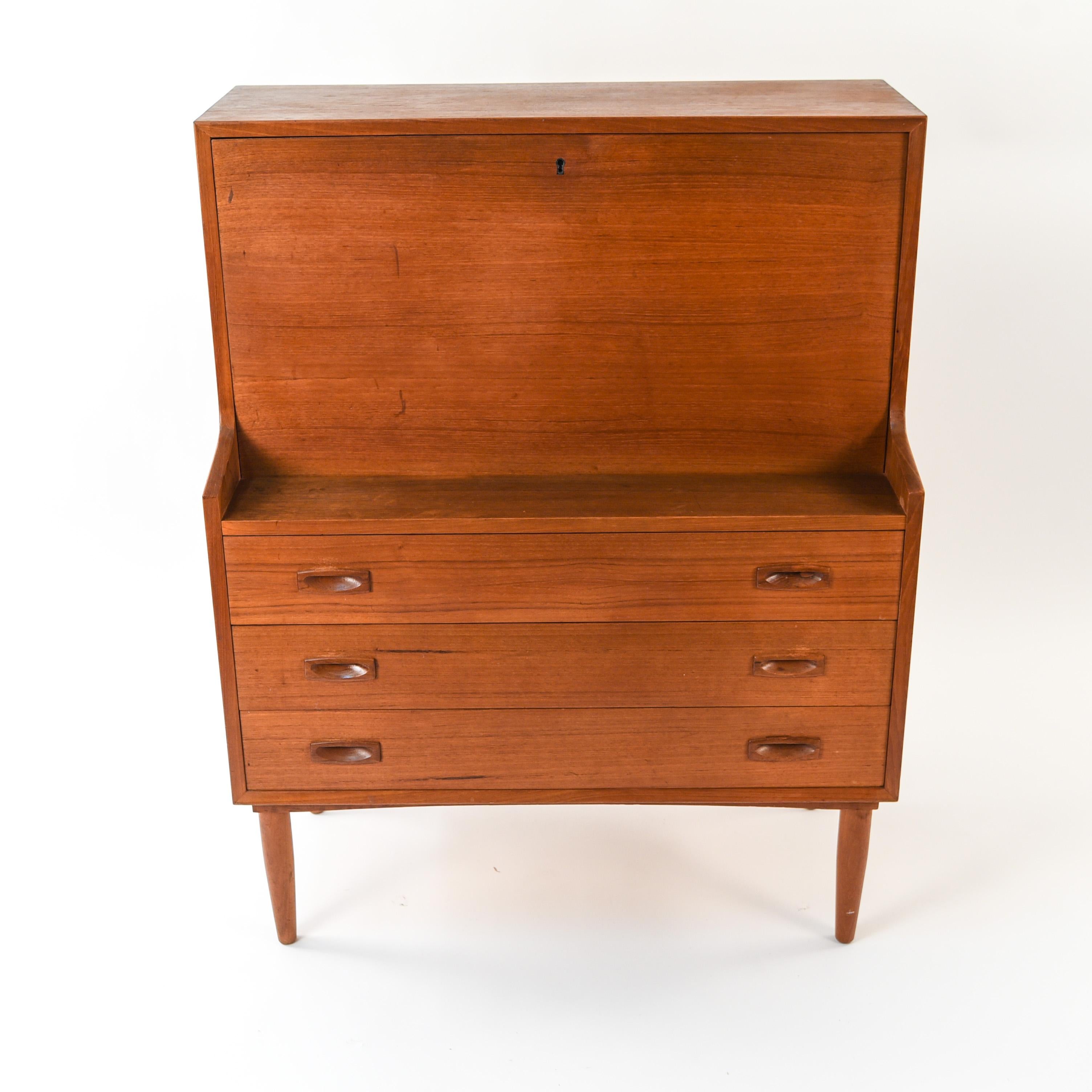 This Danish midcentury secretary is made of teak wood and features sleek, clean lines. With recessed handles and rounded legs. Includes key.