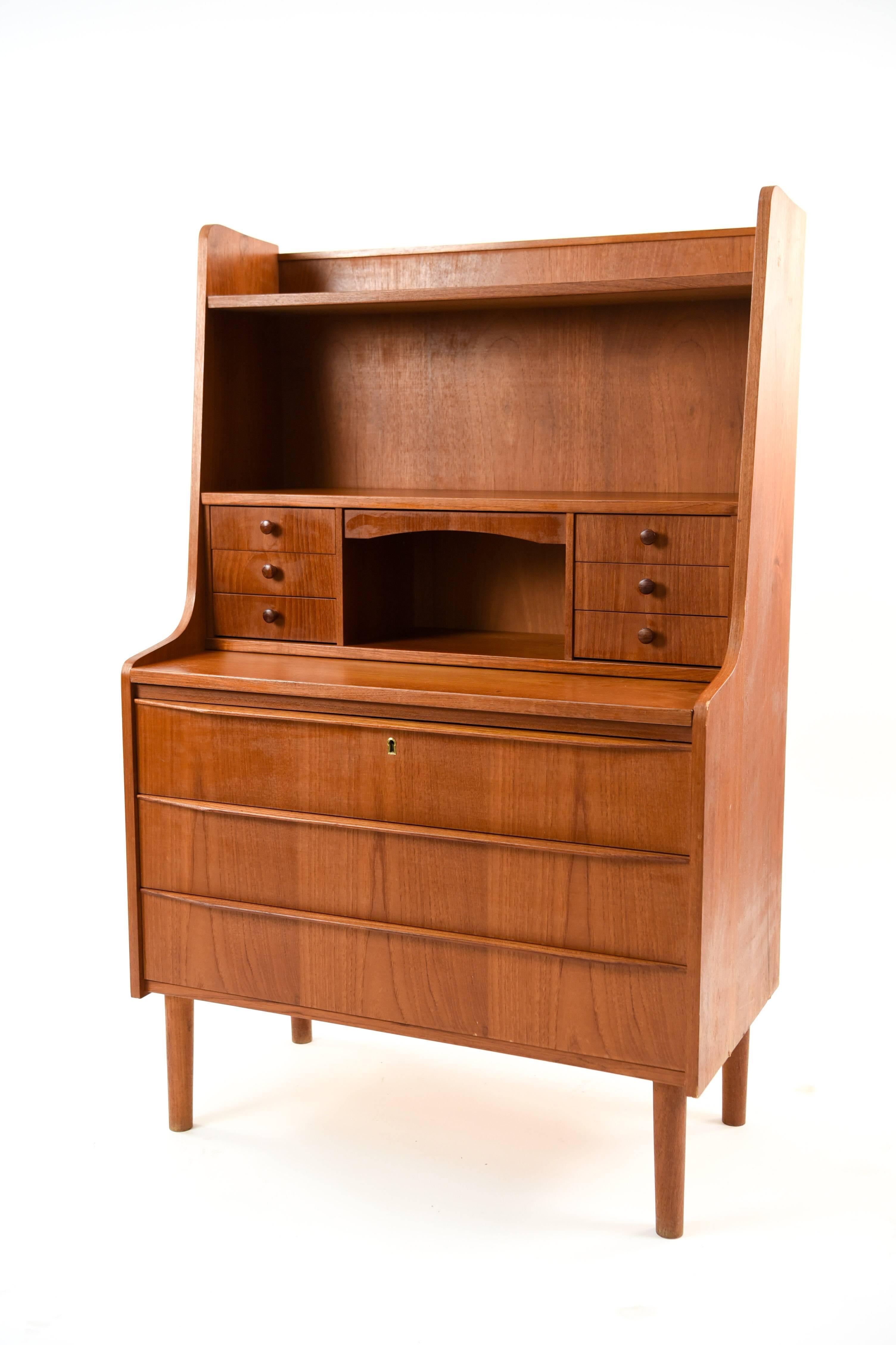 This Danish midcentury teak secretaire/secretary desk provides a great amount of storage in the larger drawers below and the smaller drawers above next to the writing surface.