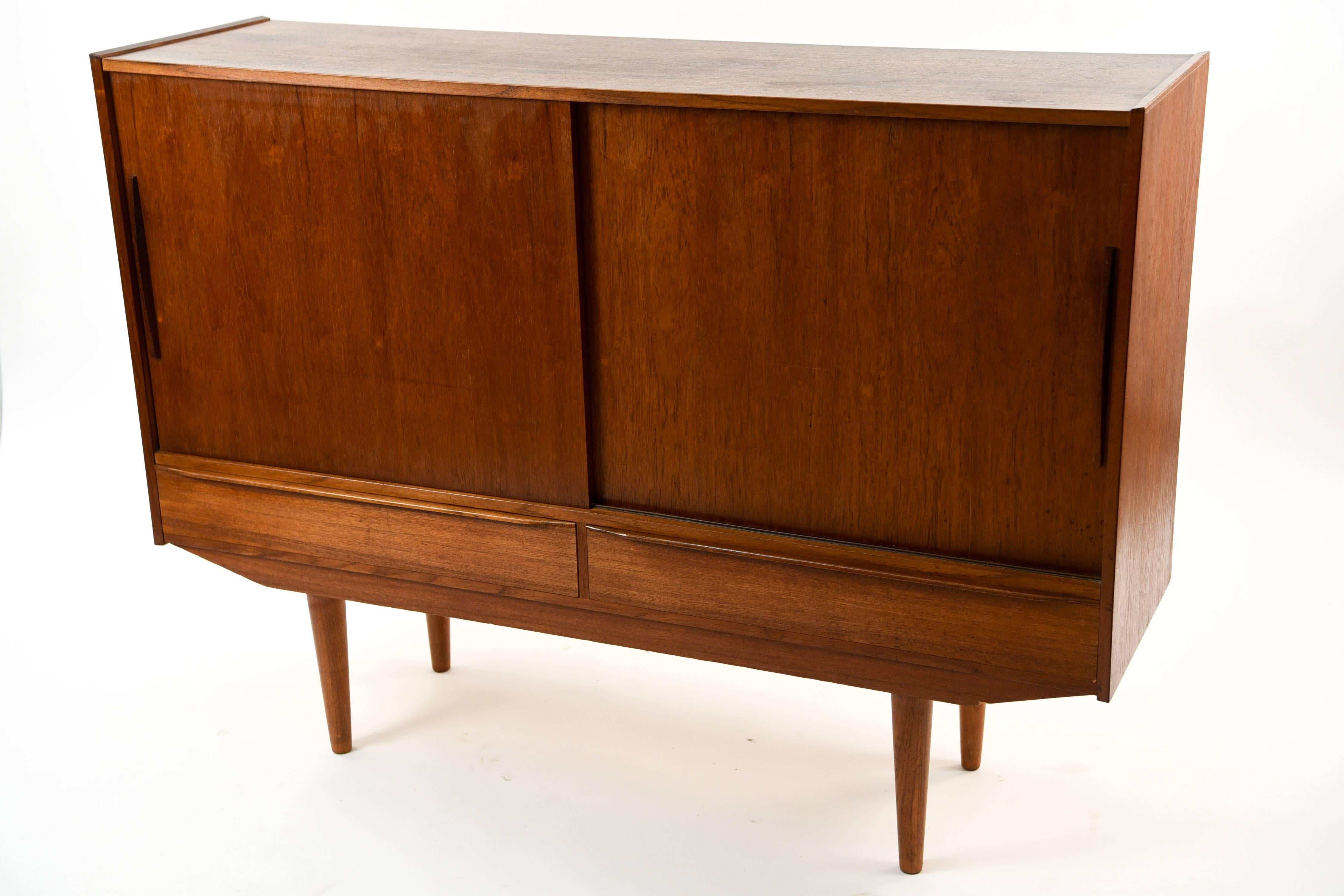 This Danish midcentury teak sideboard has style in every detail. From the handsome appearance of the sliding doors outside, this sideboard opens to reveal sliding drawers and shelves, backed with a fun design on the mirrored surface.