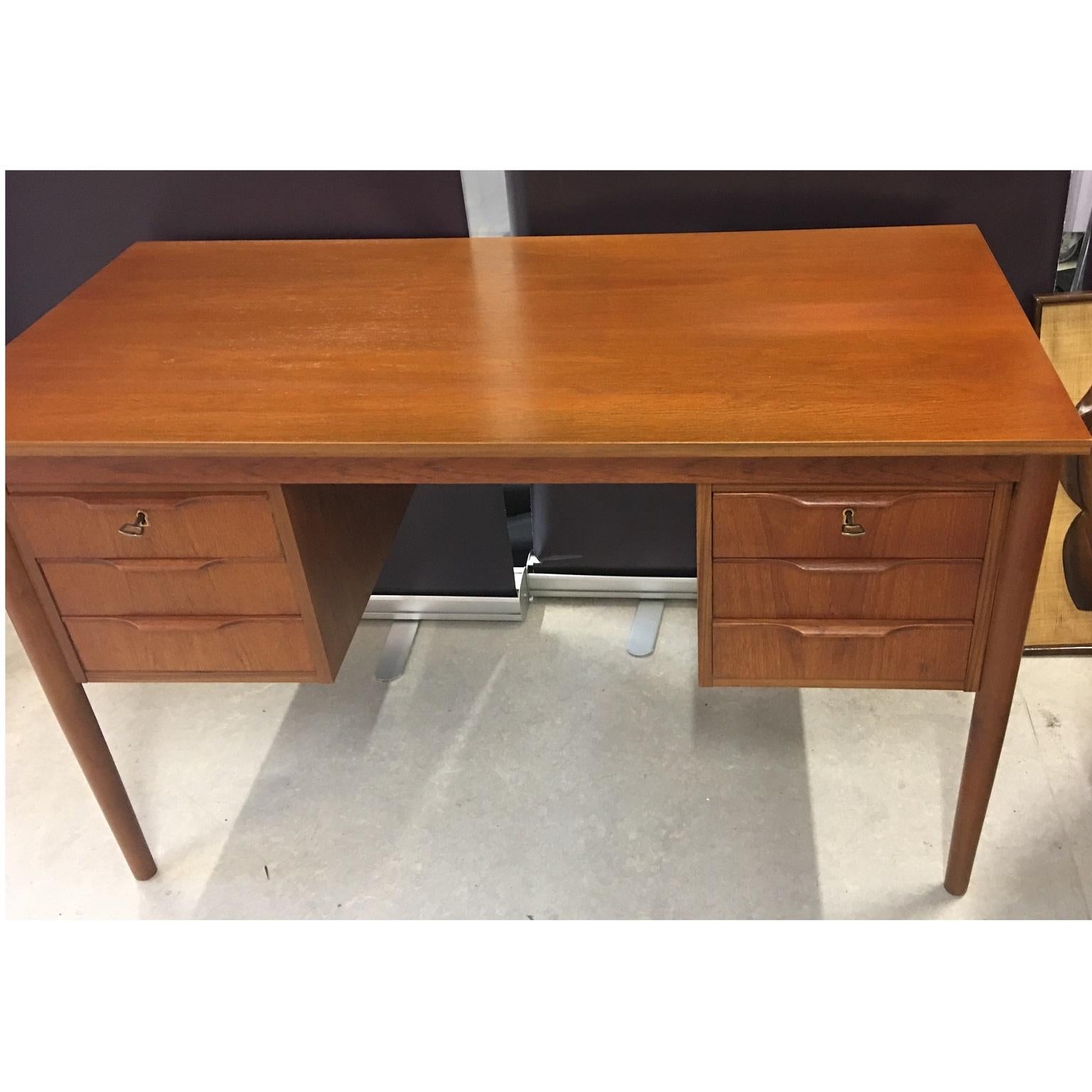 Danish midcentury teak writing desk with six drawers, circa 1960s.

A Danish midcentury teak writing desk with 6 drawers, the top one on both sides are lockable with a key. Tactile drawer handles that protrude slightly. Four main legs taper
