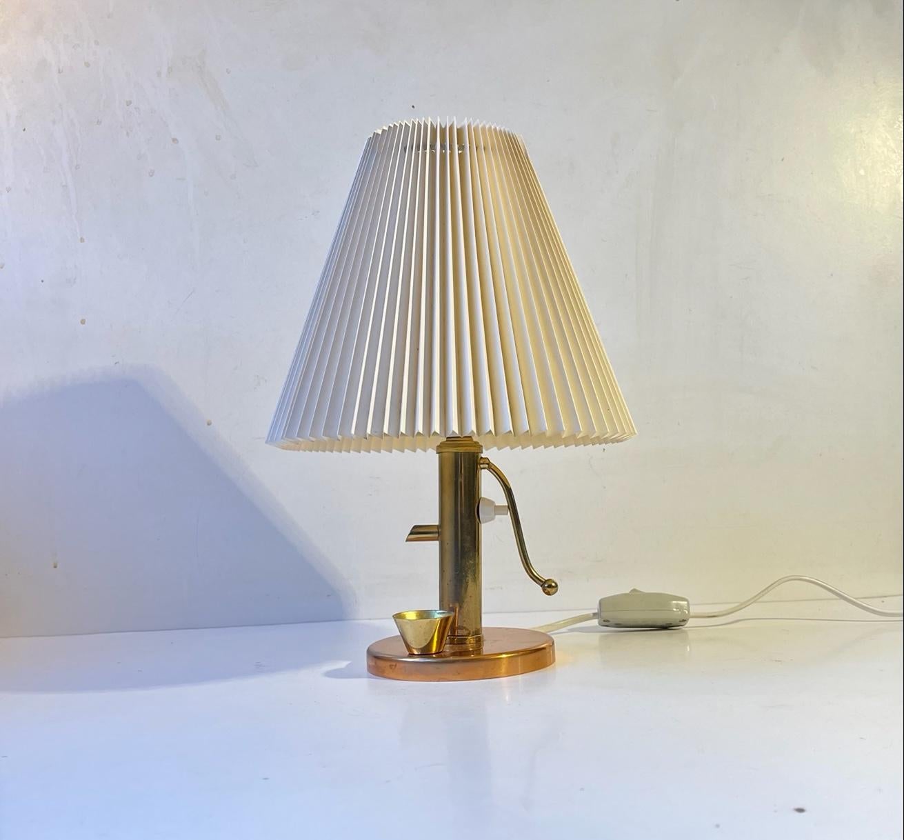 Romantic Novelty. Elegantly crafted water pump table lamp with pleaded shade. Its made from solid copper and brass. Made in Denmark during the 1960s. Measurements: Height: 31 cm, Diameter: 21 cm (shade).