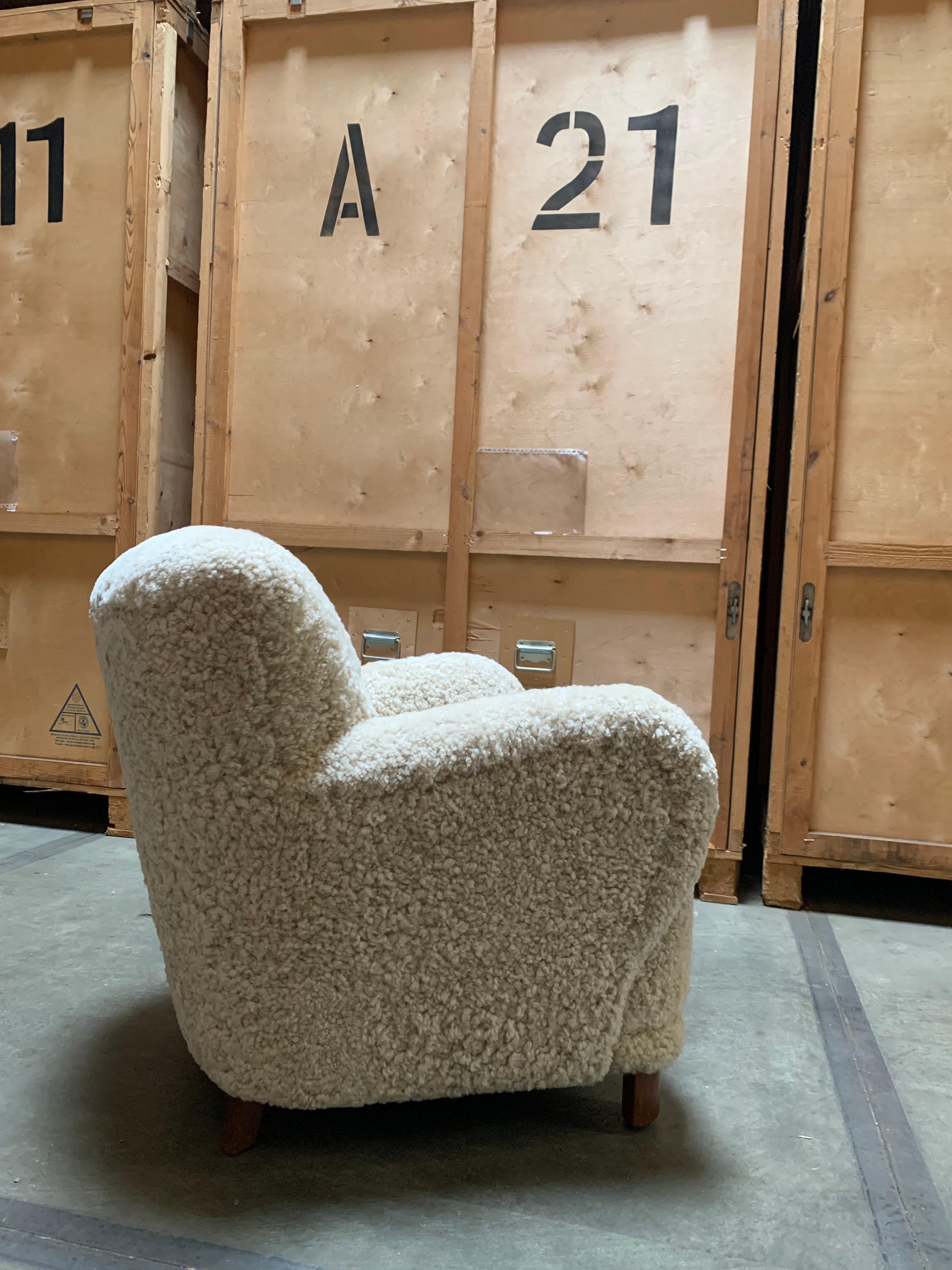 Danish modern furniture maker 1940s sheepskin armchair with beautiful lines from every angle. A daring chair design with wide armrests that invite you to come and sit. The wide back and the very large armrests give the chair character and a