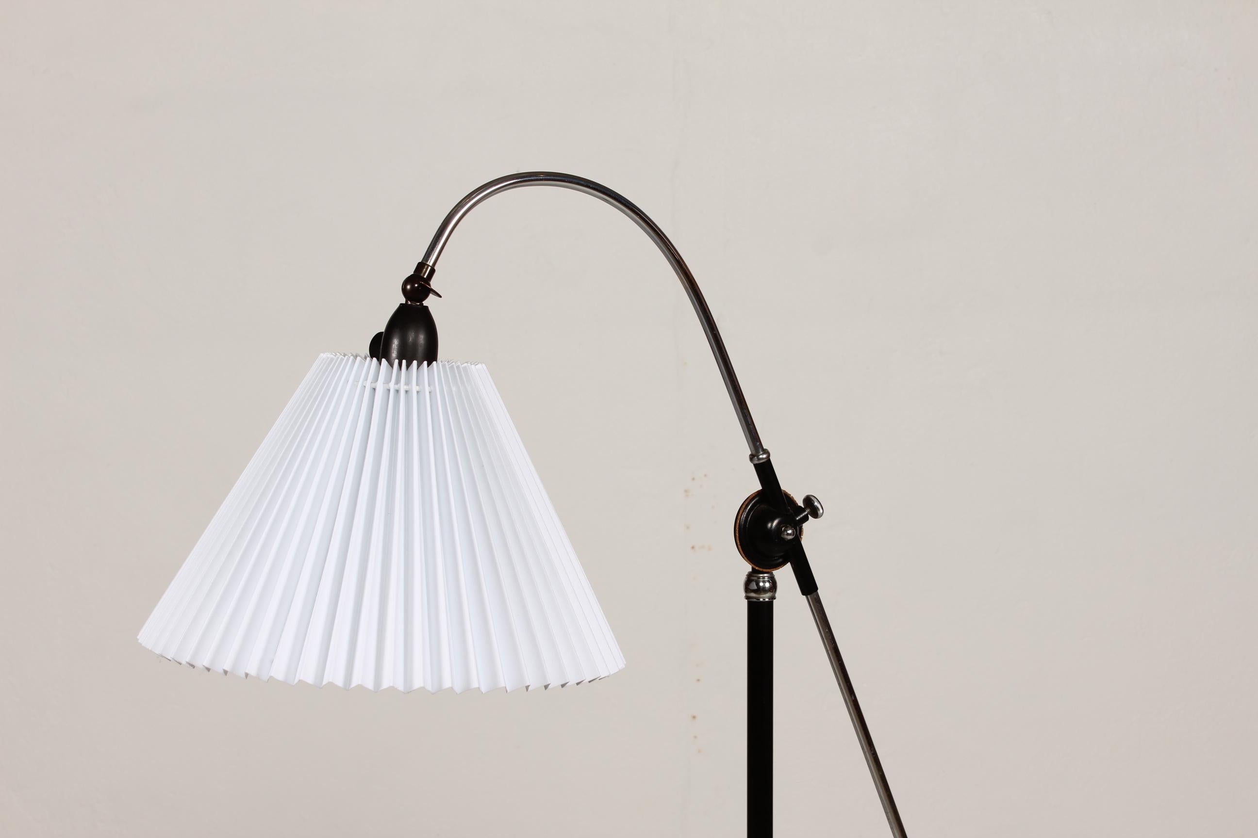 Danish modern floor lamp from the 1950s made of chrome-plated and black lacquered metal with a lamp base of cast iron. 
The new white pleated lamp shade is adjustable
The minimum height of the lamp is 148 cm. The diameter of the shade is 31