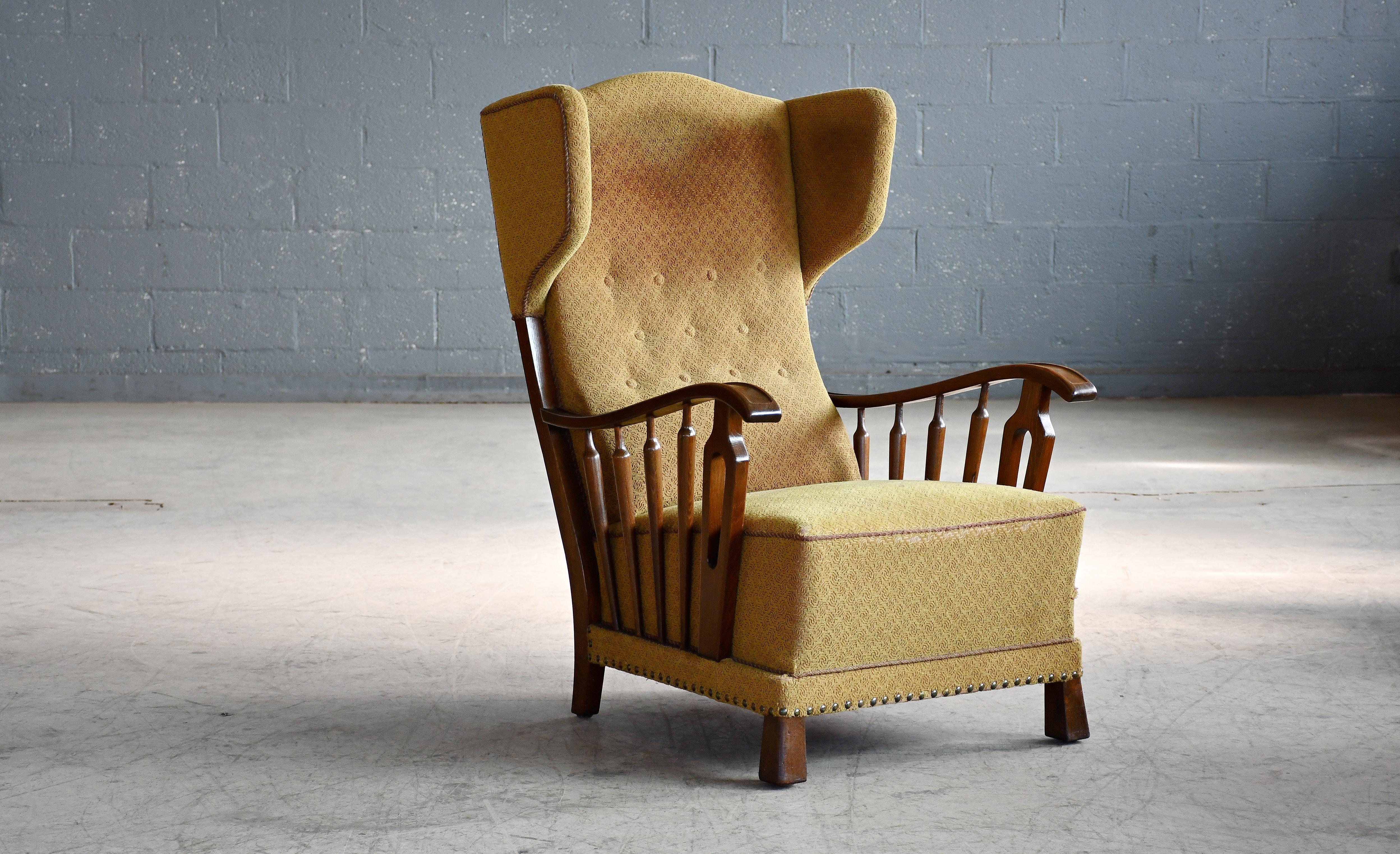 Beautiful and very unique Danish 1940s wingback  chair with nicely carved armrest in stained beechwood. Very elegant with strong angular lines and a strong presence to anchor any room. Solid and sturdy build quality and very comfortable.  Just noble