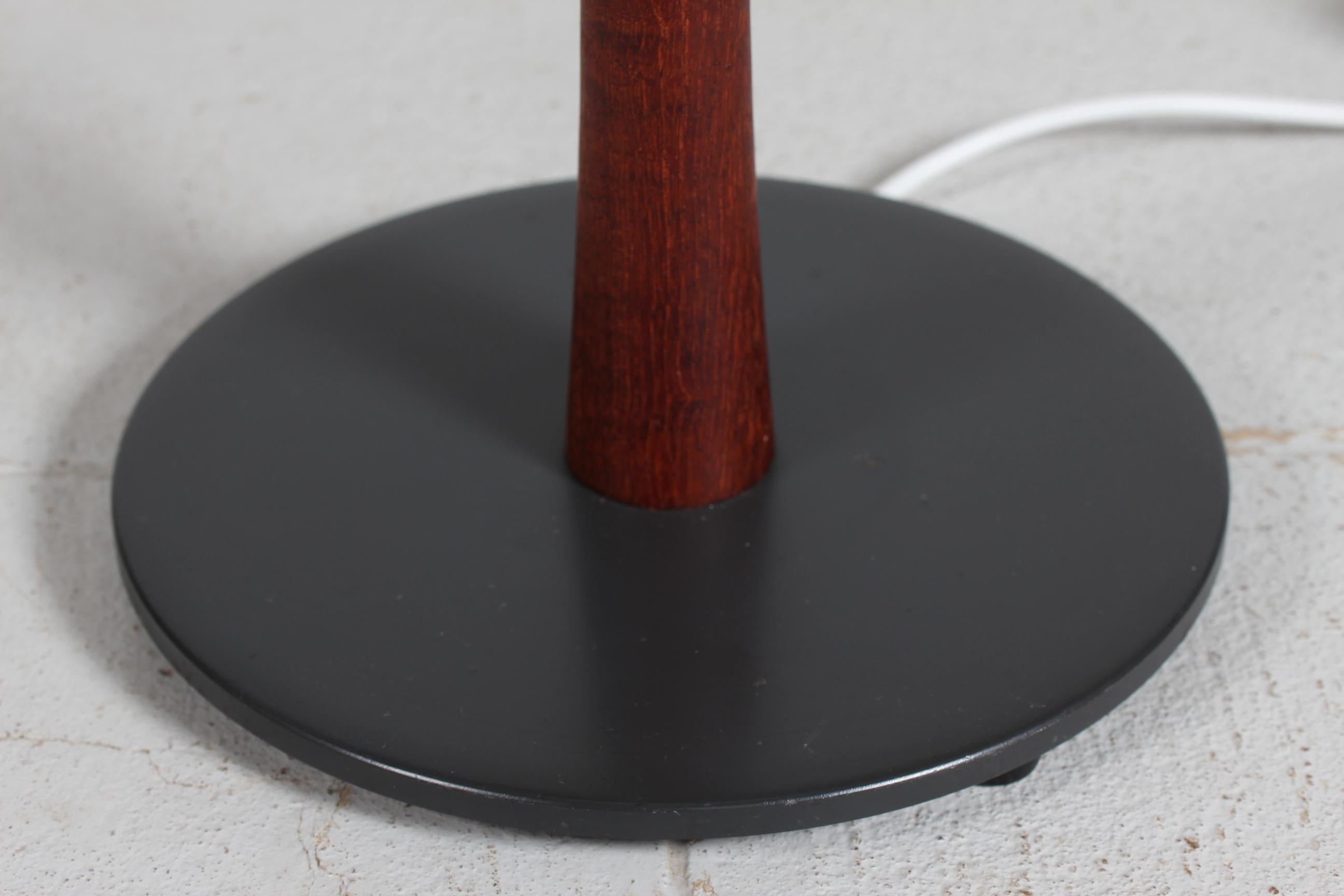 Danish lightning design, floor lamp from the 1960´s made of teak and with lamp foot of black lacquered metal.

Included is a new lampshade designed in Denmark.
The shade is made of woven fabric with some texture and the color is white. It has a