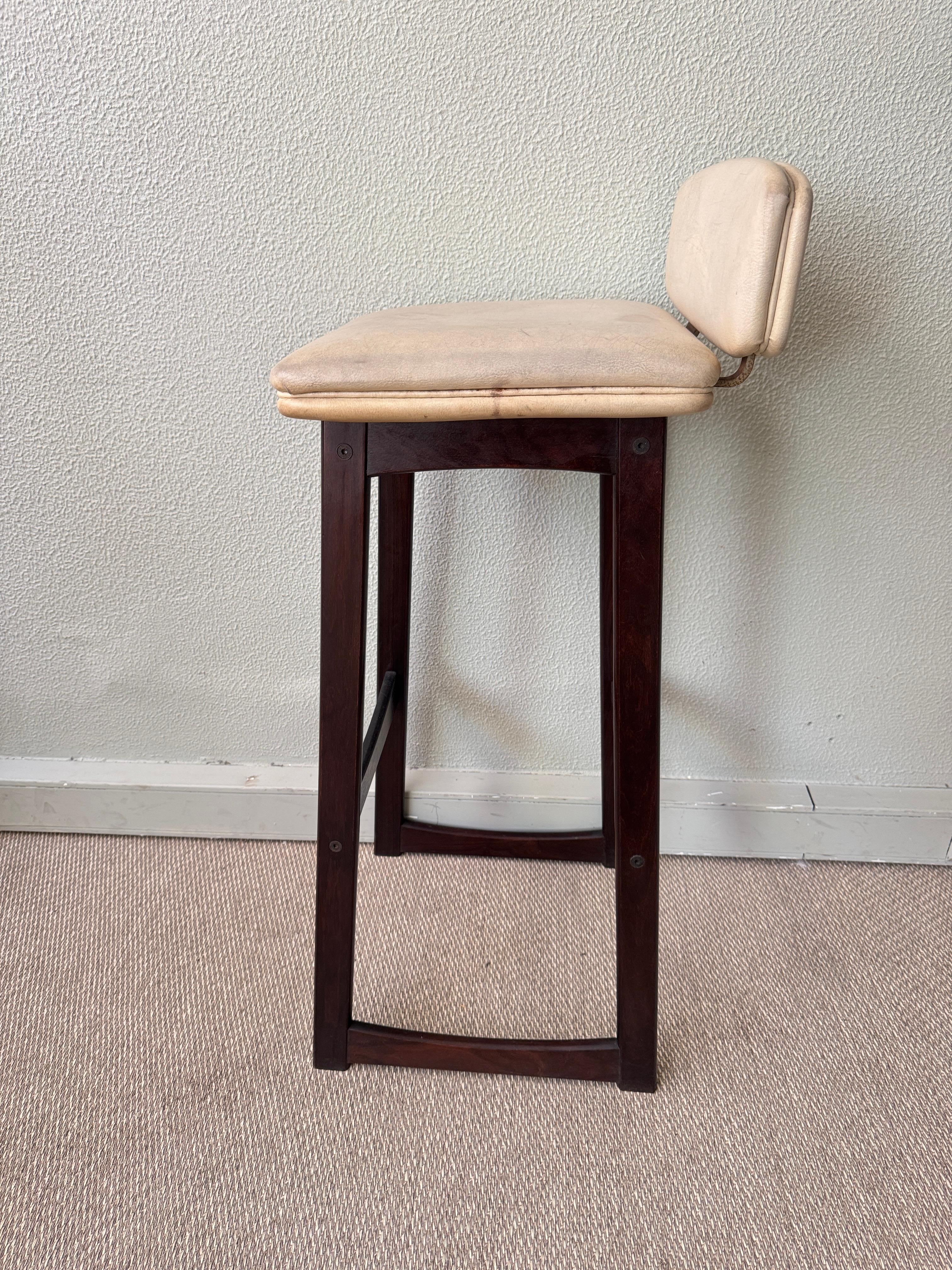 Ce tabouret de bar moderne danois à dossier bas, datant des années 1960, est un bel exemple de l'artisanat scandinave et du design fonctionnel. Construit en hêtre massif teinté foncé, le tabouret se définit par ses lignes architecturales épurées et