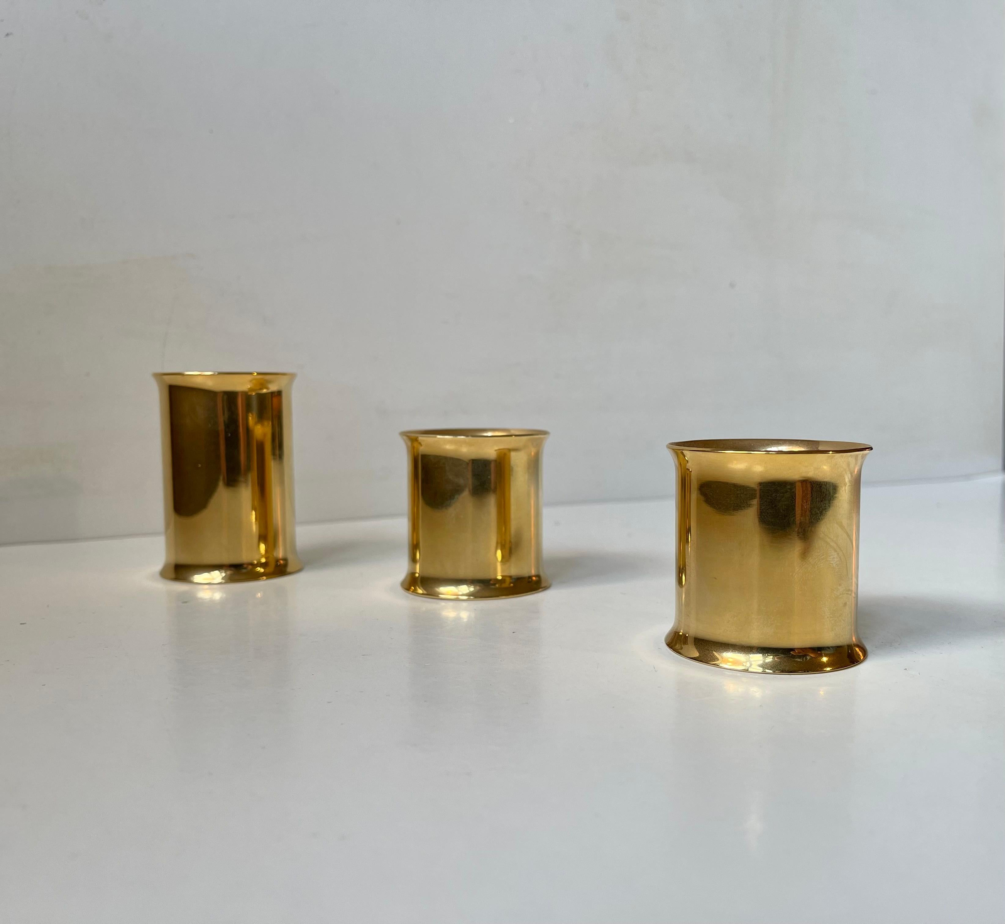 A set of 3 danish modern chimney shaped candleholders. Made from 24 carat gold plated brass. they can be installed with either tea lights (one side) or church/bloc candles. (other sides. Reminiscent in design to similar candleholder by Hans Agne
