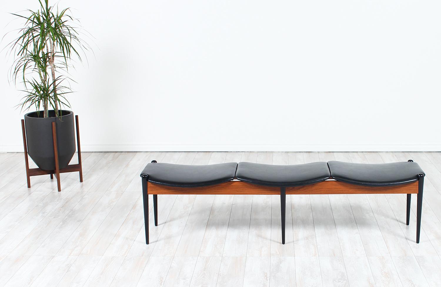 Sleek 3-seater bench designed and manufactured in Denmark circa 1950s. Featuring three newly upholstered seats in full grain black leather that rests over a teak wood frame. The tapered black-lacquered wood legs complement the black upholstery