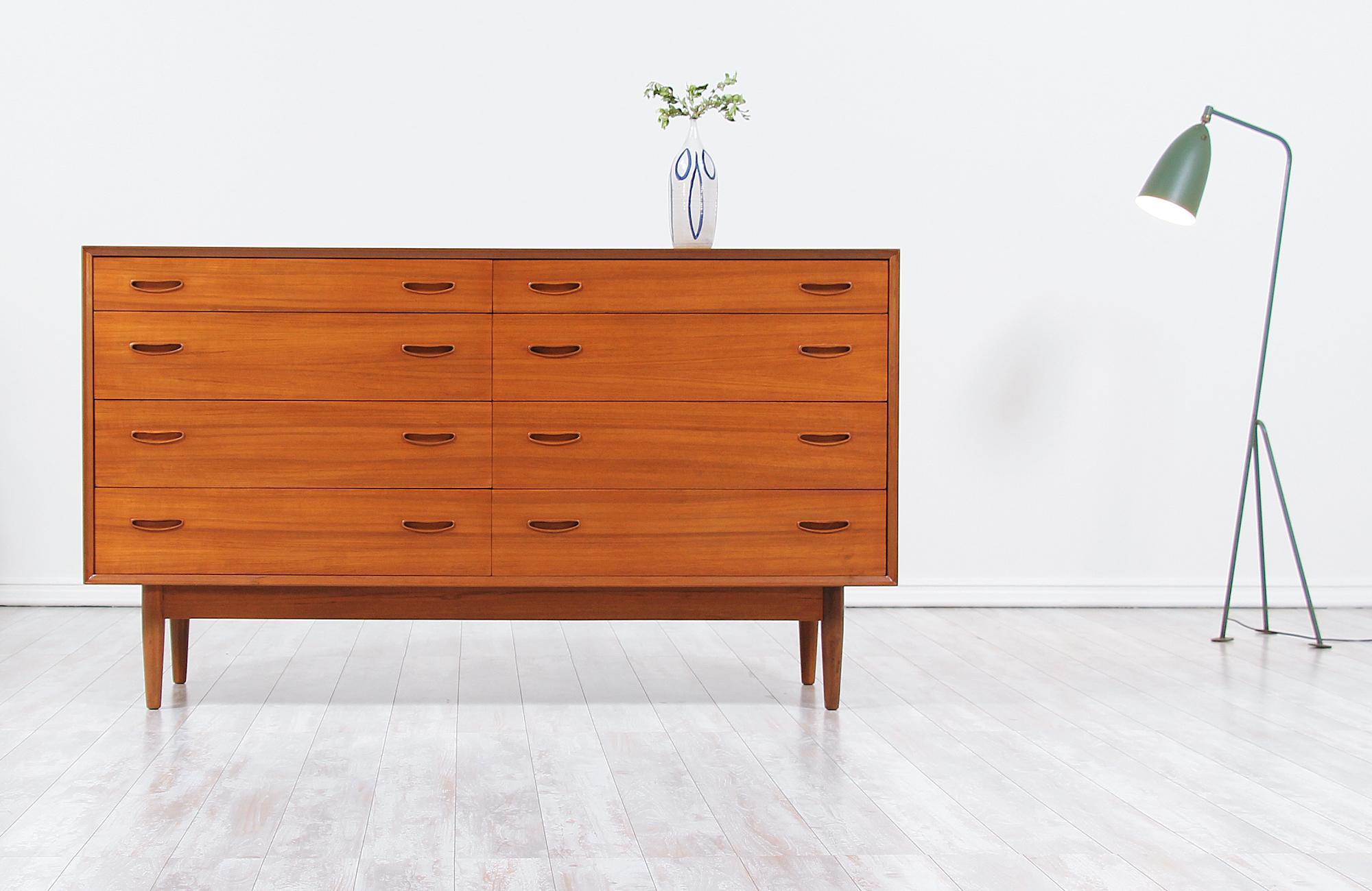 Stylish Danish modern dresser designed and manufactured in Denmark circa 1960s. This dresser features a solid teak wood frame sitting on four tapered legs with wooden stretchers for optimal support. Each of the eight drawers shows two ‘smiley’