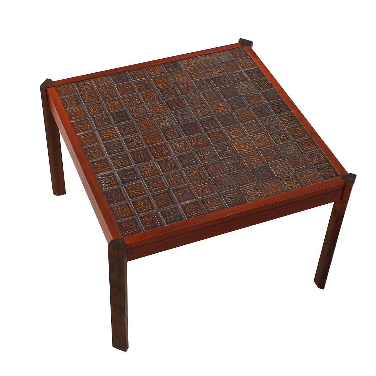 Hier ist ein interessanter Danish Modern Tisch. Der Rahmen ist hell mit kontrastierenden dunkleren Beinen. Die Tischplatte ist mit Fliesen in verschiedenen Rotbraun-Tönen bedeckt, die die beiden Holztöne perfekt miteinander verbinden. Die Fliese ist