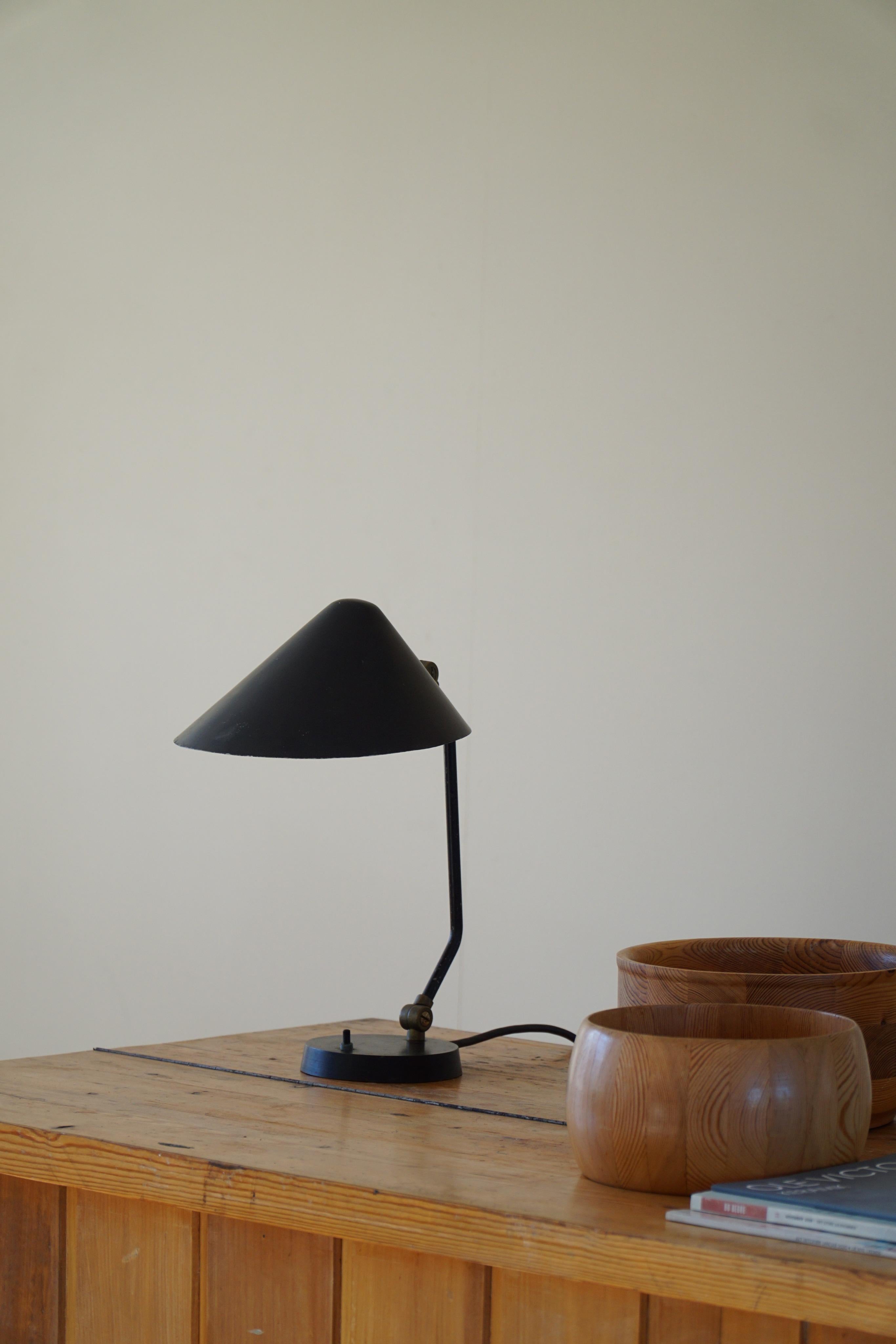 Rare and elegant adjustable table lamp in black lacquered metal from the 1950s. Made by the Danish company Louis Poulsen. 
The light can be directly pointed at a subject as well as turned against a wall for more soft light. 

Some traces of