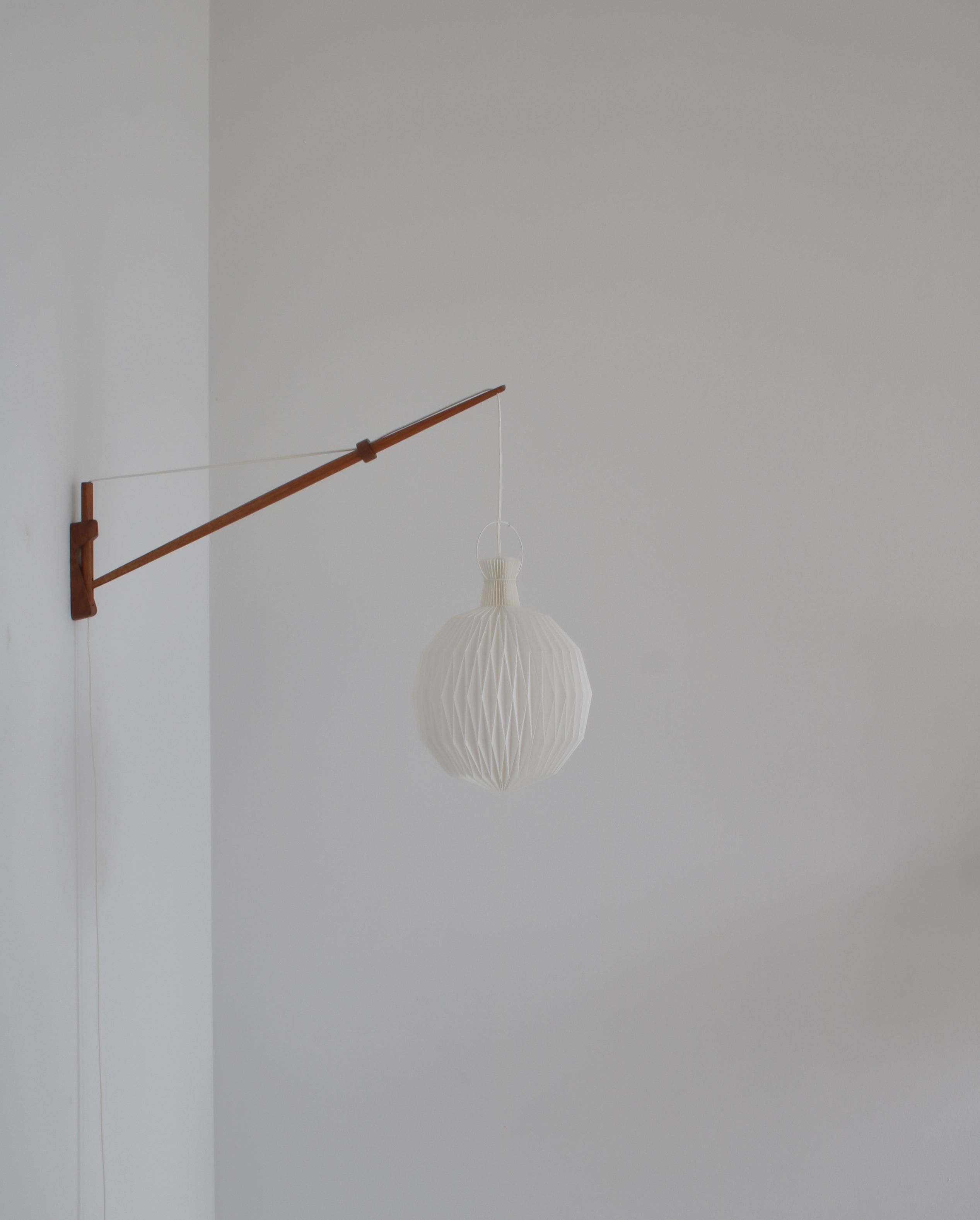 Adjustable wall lamp in patinated oak made in the 1950s by designers A. Bank Jensen & Kjeld Iversen for Louis Poulsen, Copenhagen. The lamp can be adjusted in any directions and angles simply by pulling or releasing the wire. The lamp features a new