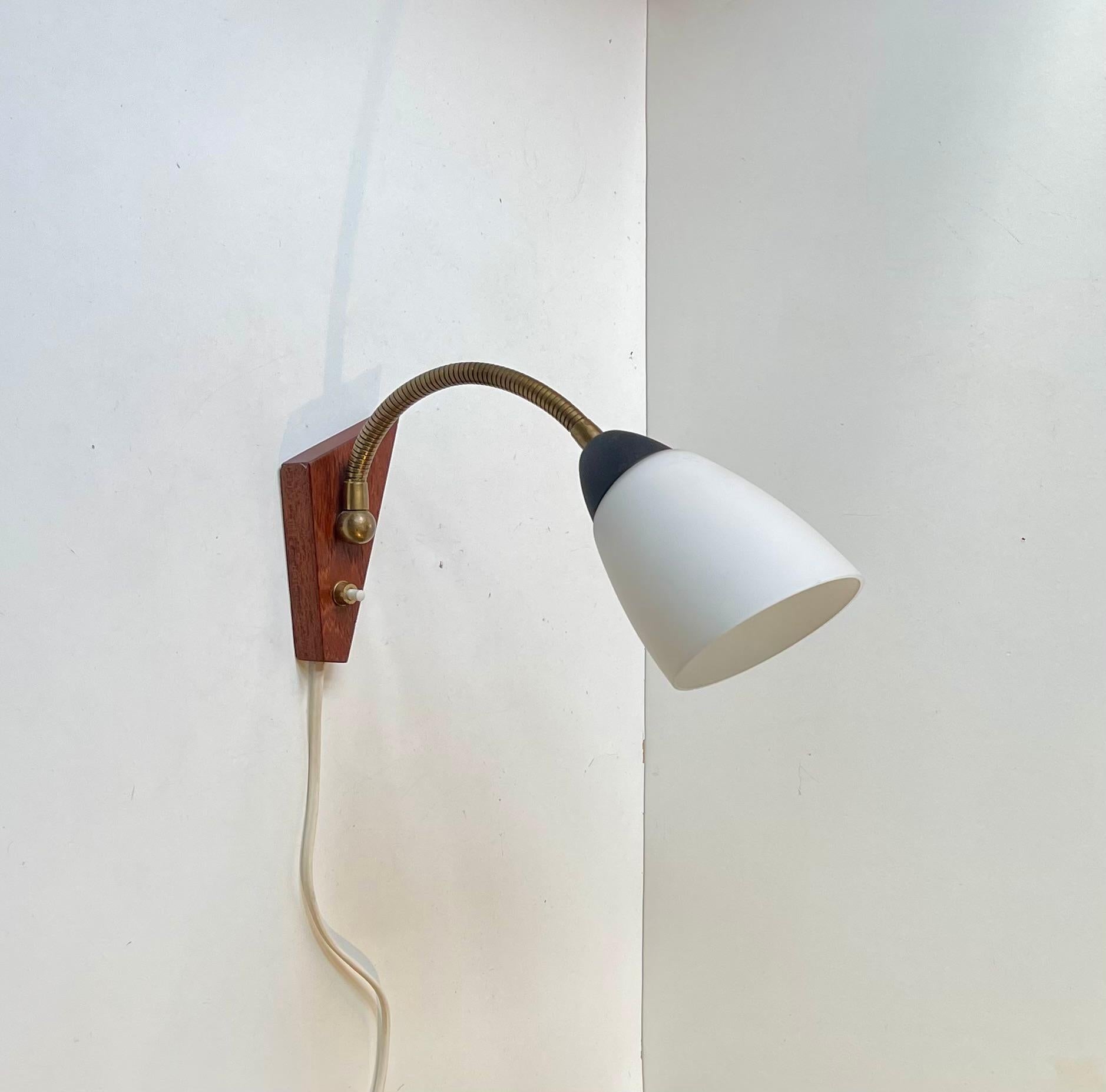 Aplique regulable fabricado en Dinamarca hacia los años 50-60. Presenta una pantalla de cristal blanco entubado, una montura de teca maciza y un cuello de cisne flexible de latón. Con un estilo inspirado en el fabricante italiano Stilnovo y en el
