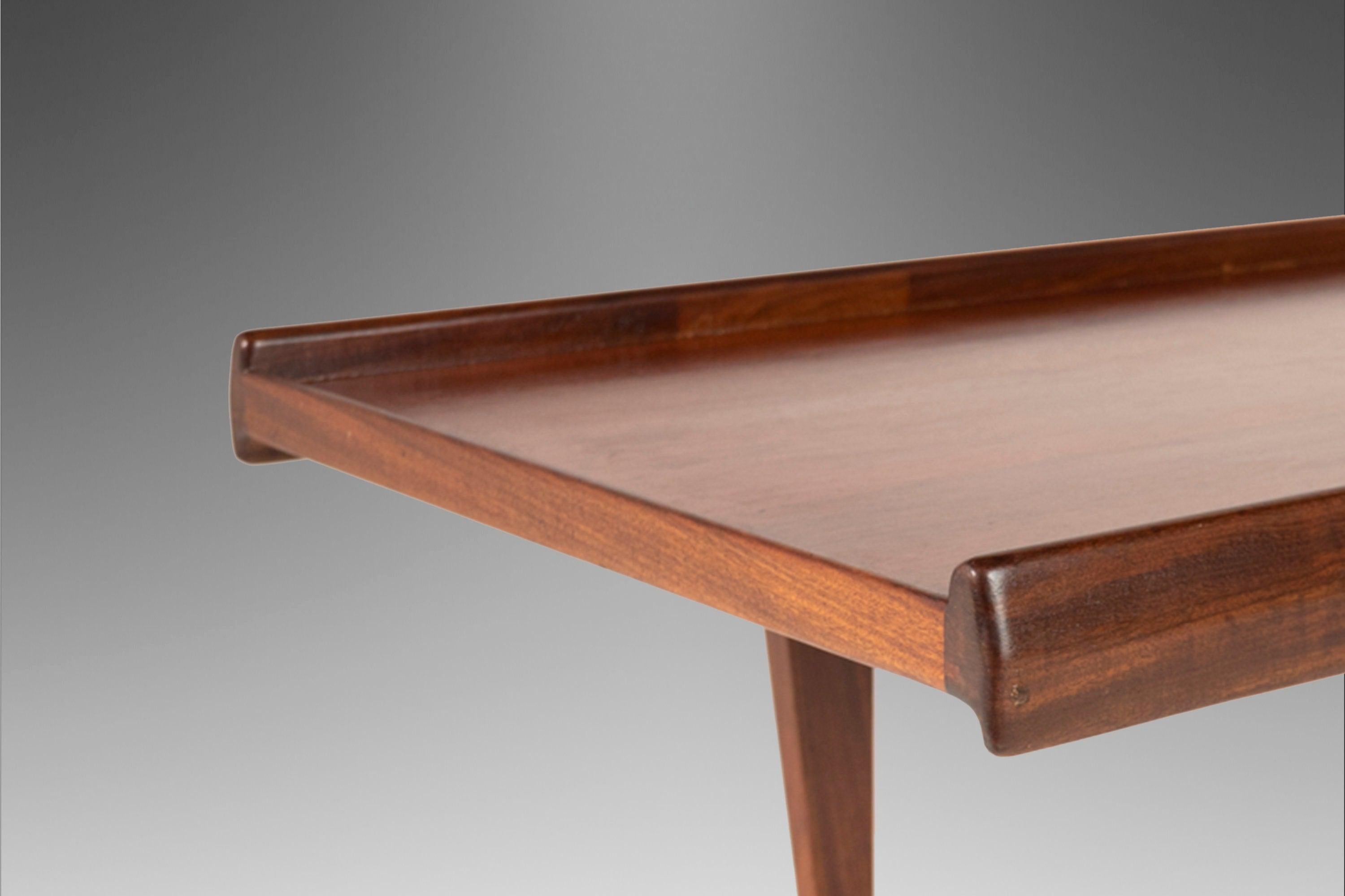 As architecturally fascinating as it is aesthetically pleasing this iconic coffee table, designed by Peter Løvig Nielsen in the early 60's, is the epitome of functional art. Featuring turned edges built of solid teak with exceptional woodgrains set