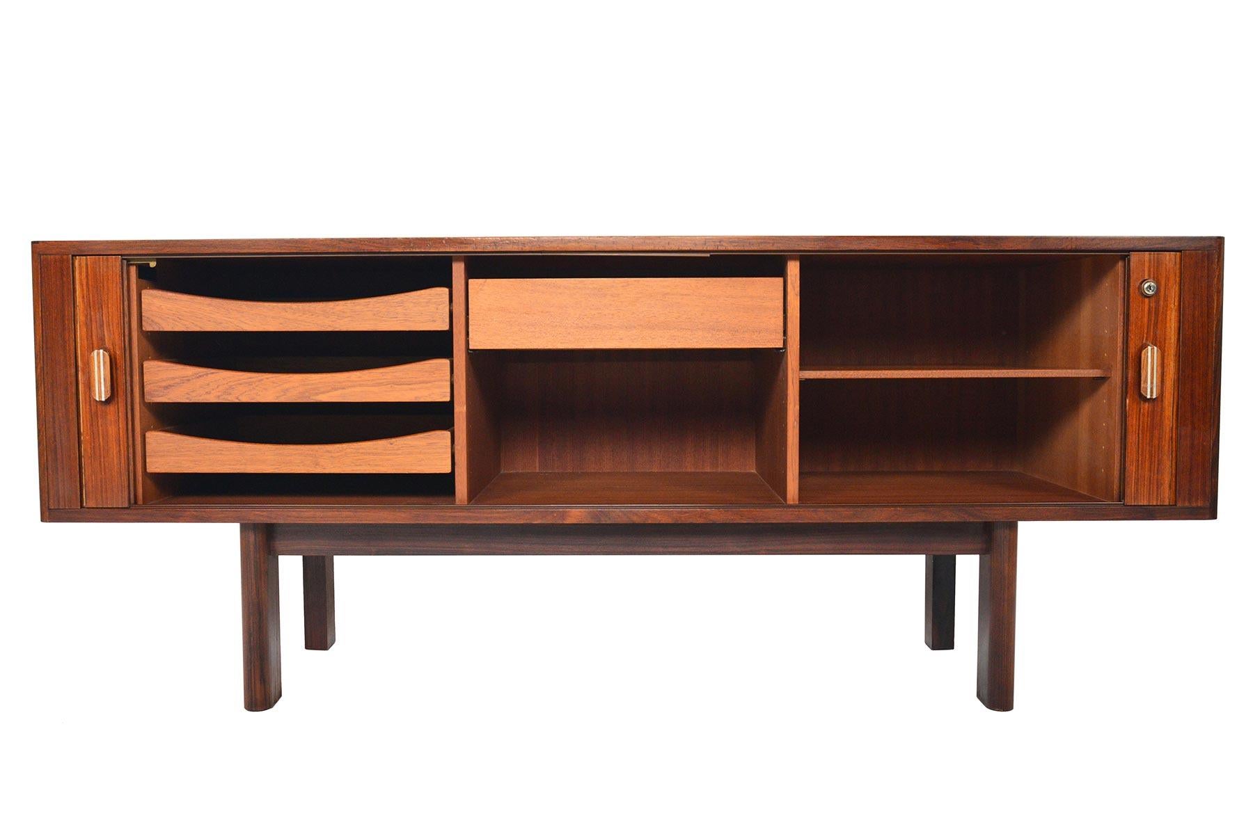 This Danish modern Brazilian rosewood tambour door credenza Model 237 was designed by Arne Vodder for Sibast and features a sleek profile and ample storage! This low design features soft corners and a sculpted base. The smooth running tambour doors