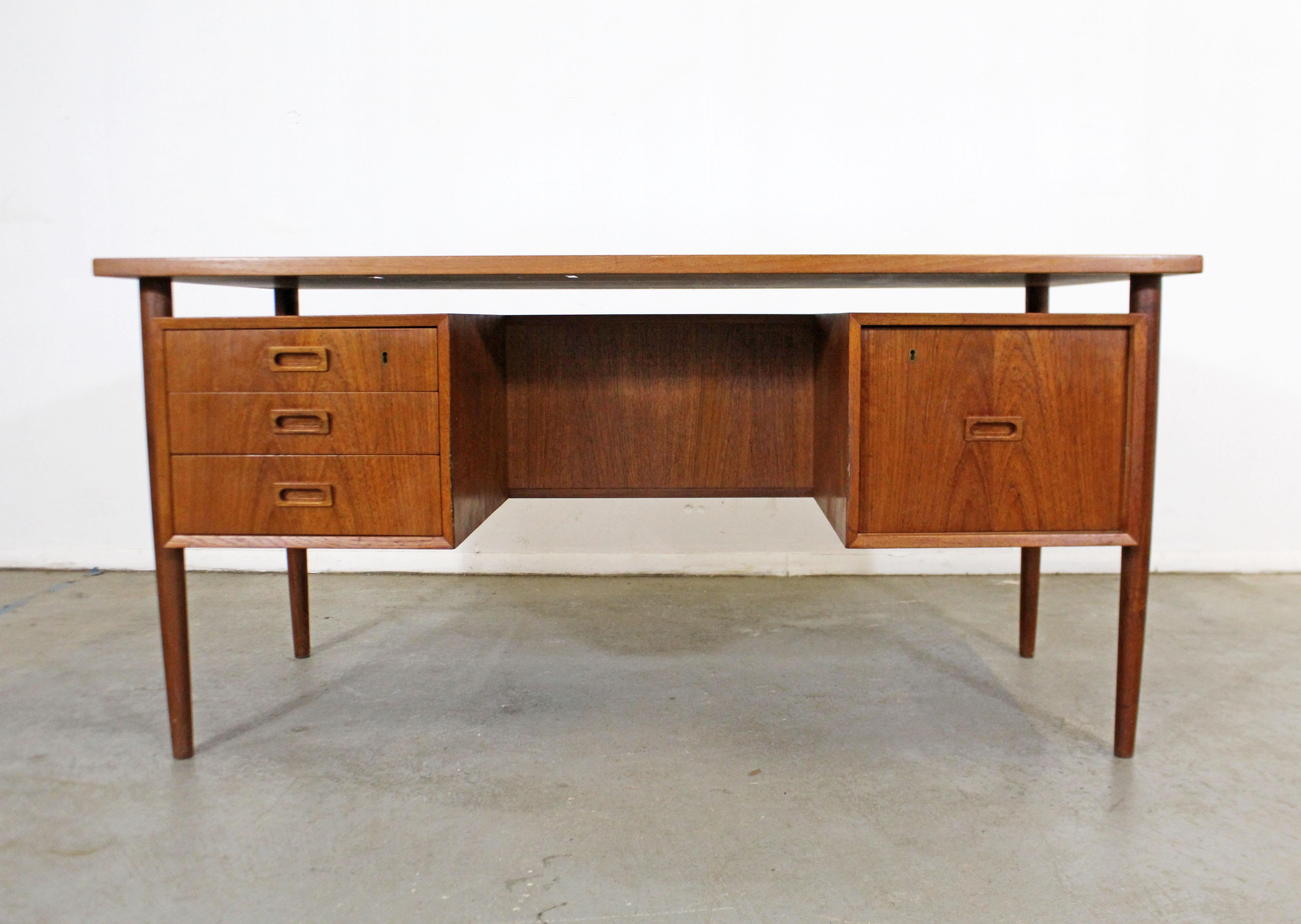 Offered is a beautiful Danish modern desk made by Bornholm of Denmark featuring a floating top and full-front shelf. It has three drawers on the left and a file cabinet on the right. The desk is in good vintage condition, showing some wear from age