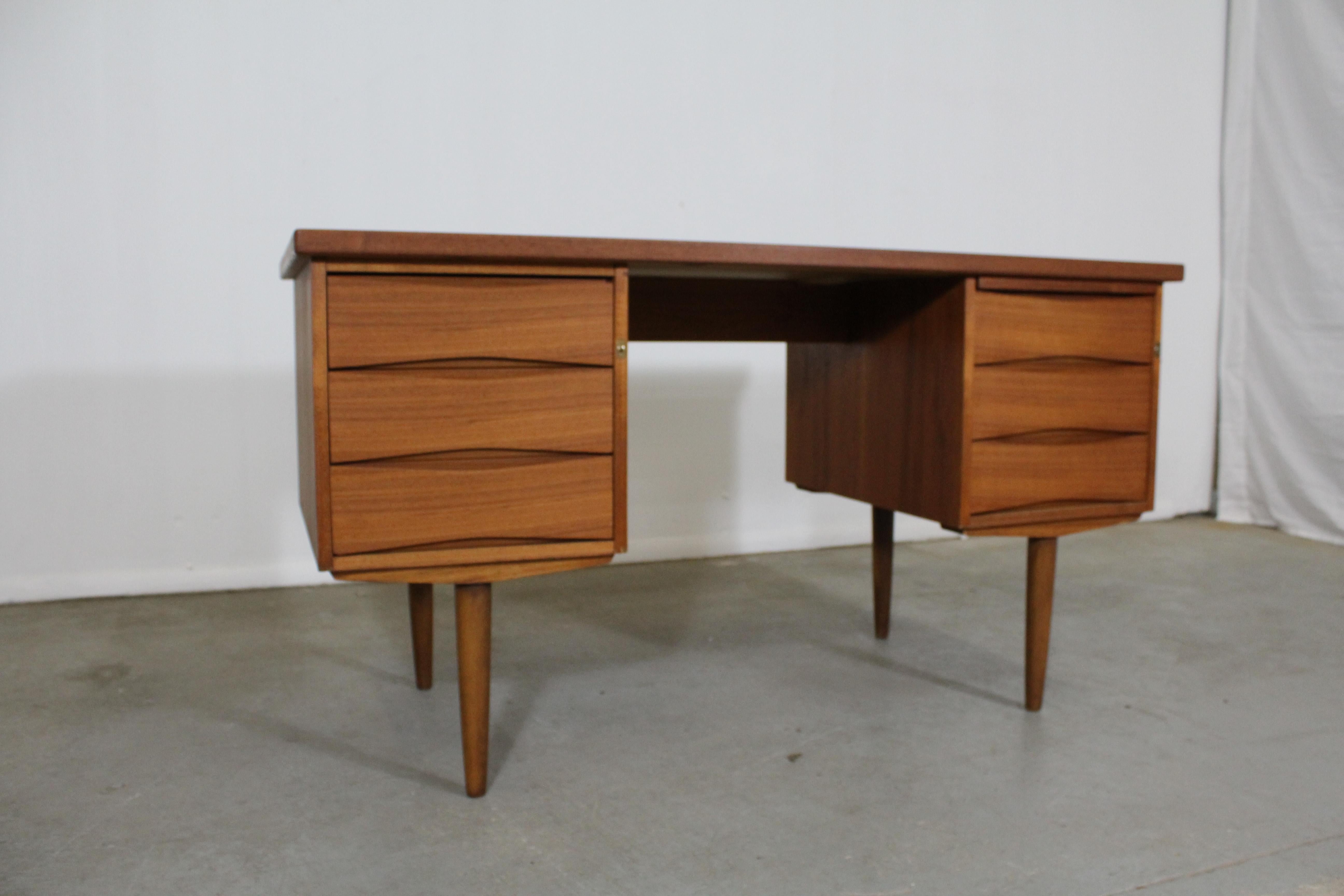 Danish modern Arne Vodder style desk on pencil legs.

Offered is a very cool midcentury Danish modern teak desk. This piece is made of teak. It is similar to the style of Arne Vodder. It has three drawers on either side and a pull out (see