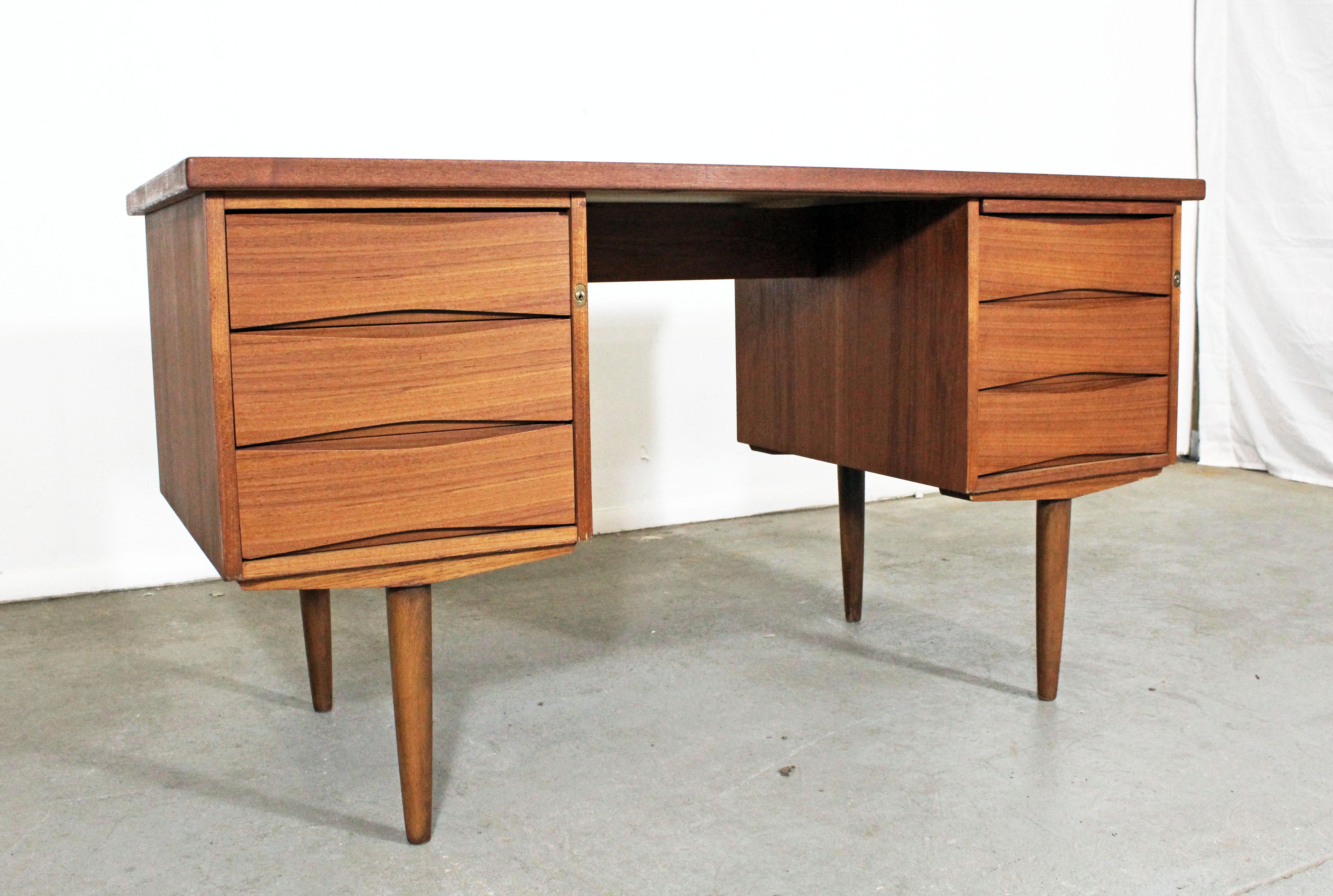 Offered is a beautiful Danish modern teak desk, similar to the style of Arne Vodder. It has three drawers with sculpted pulls on both sides and one pullout / pull-out shelf (see pictures). The desk is in very good condition, has normal age wear