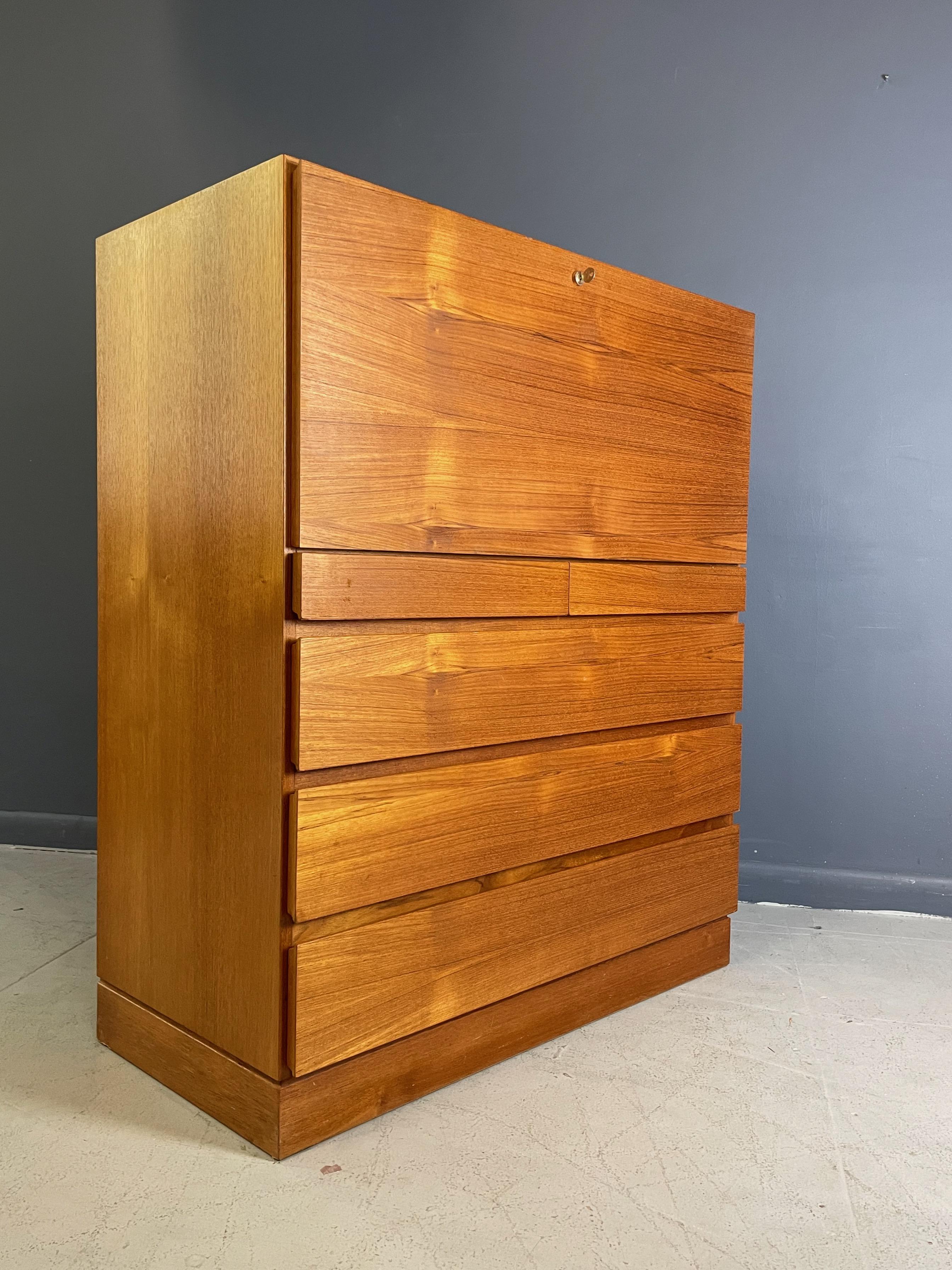 Classic Danish modern cabinetry on this piece, a desk in teak with door that pulls down to reveal a generous work area and cubbies that can store all your needs. Below the desk are two small drawers and three large drawer providing plenty of