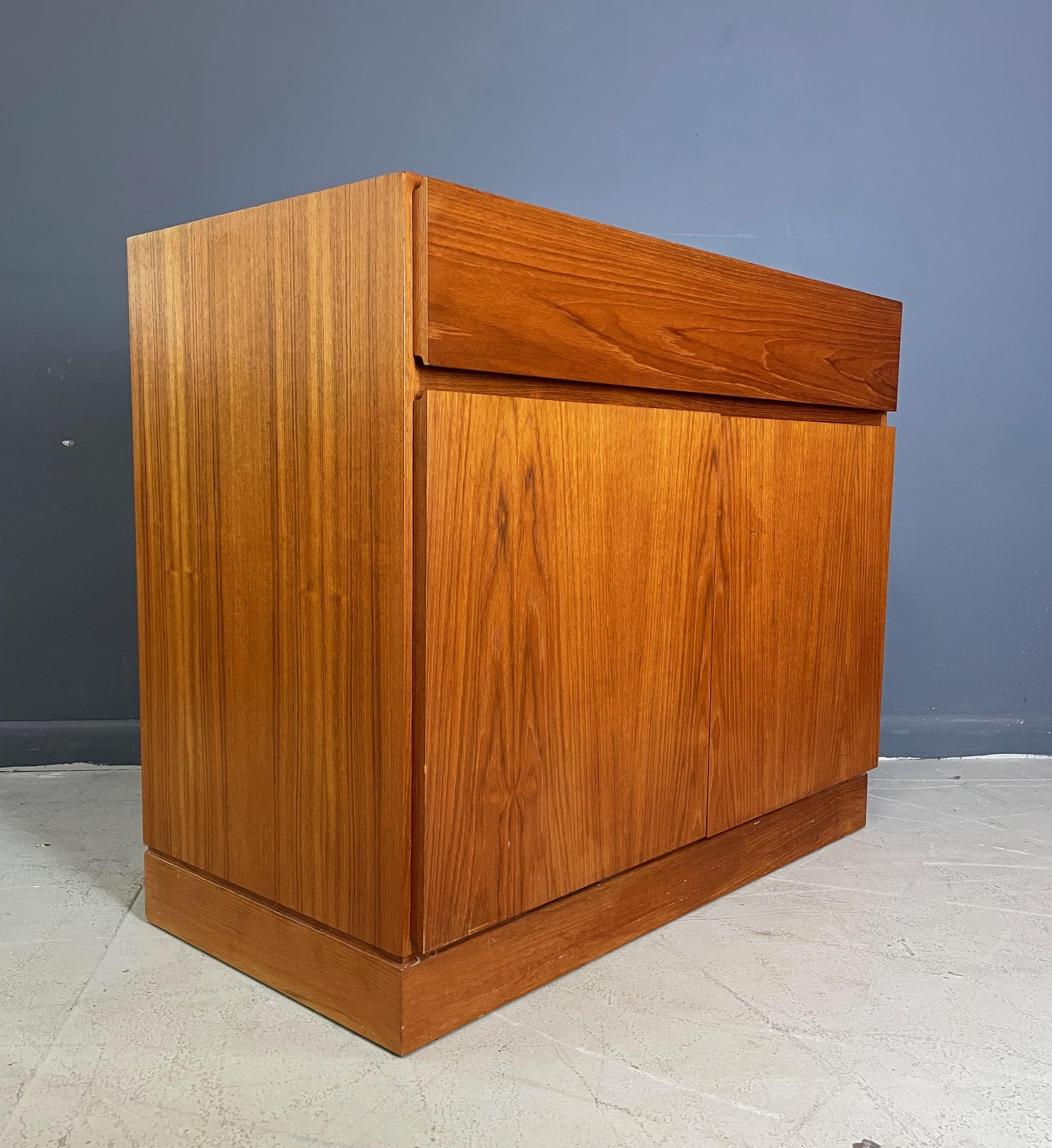 Handsome chest designed by Arne Wahl Iverson in teak by Vinde Mobelfabrik. This unusual chest has a large drawer on top with two doors underneath that open to reveal four sliding drawers on the left and a shelf on the right.