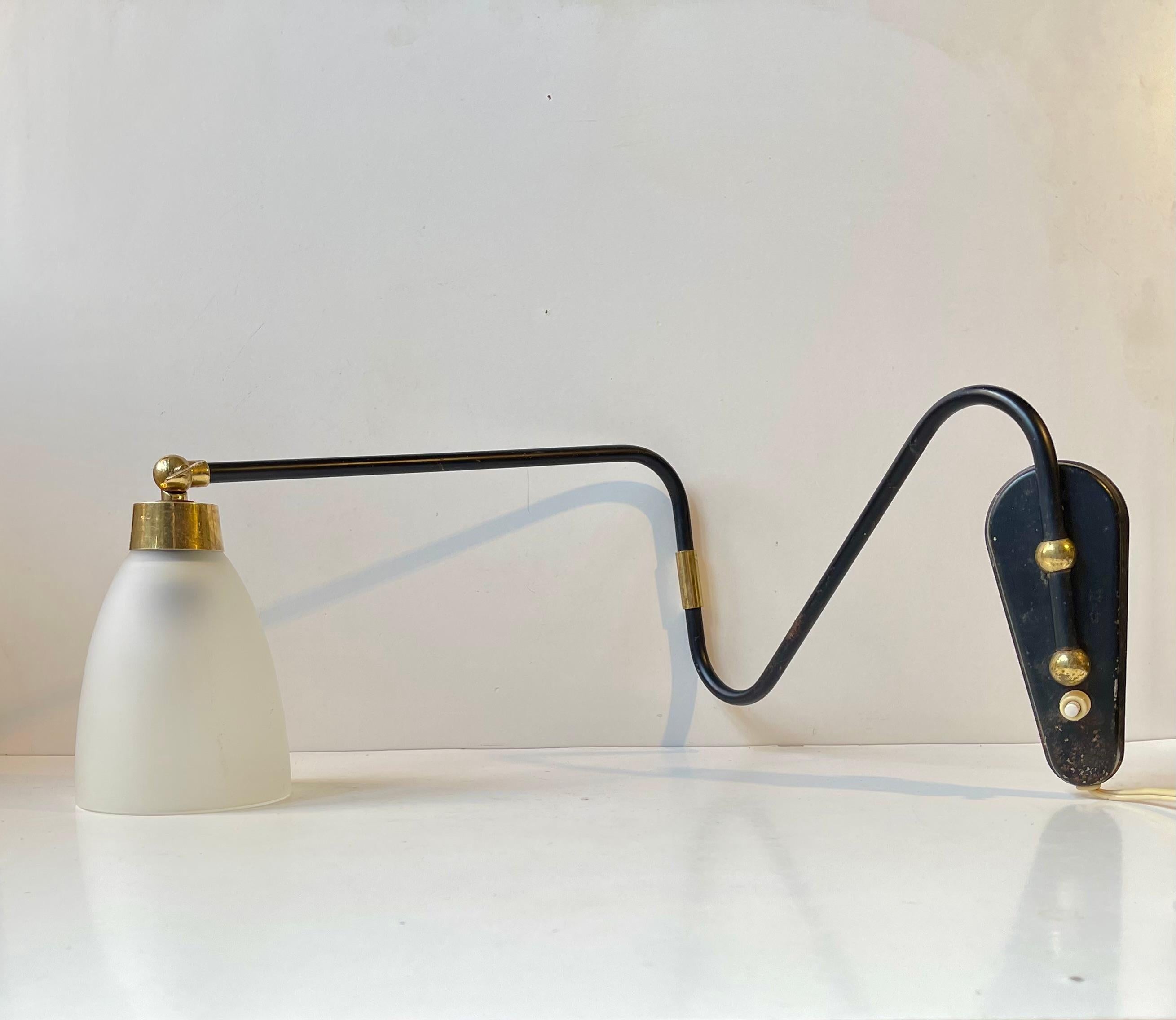 Fully adjustable wall lamp composed of a brass accented steel 'body' installed with a frosted glass shade. It was designed and manufactured by Laoni in Copenhagen, Denmark. The style is reminiscent of Svend Aage Holm-Sørensen. The shade may have