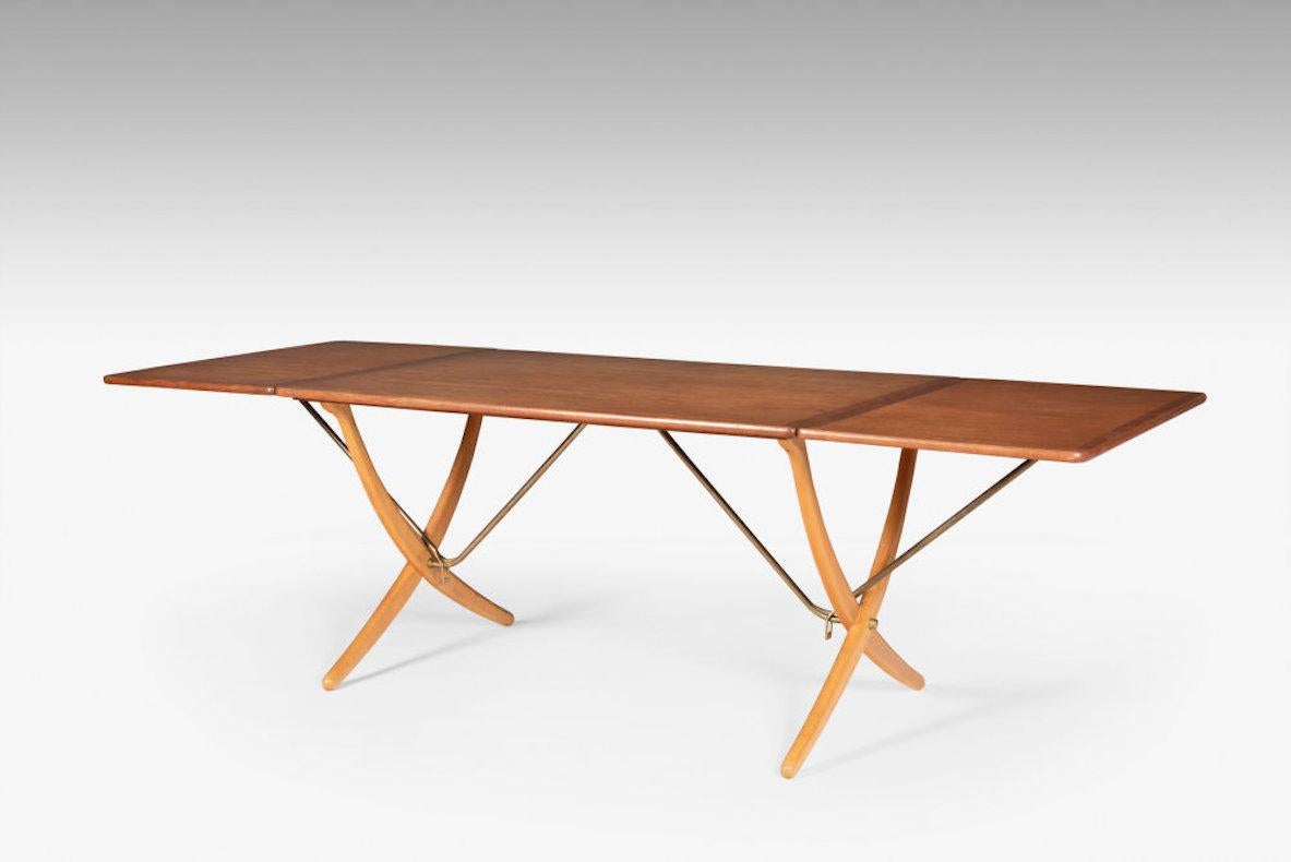 Model AT 304, also called Sawhorse,  teak table with oak legs. The folding leaf is held by a brass rod and automatically locks when  the leaf is pulled up. Beautiful patina. A perfect marriage of design and function, this dining table exemplifies