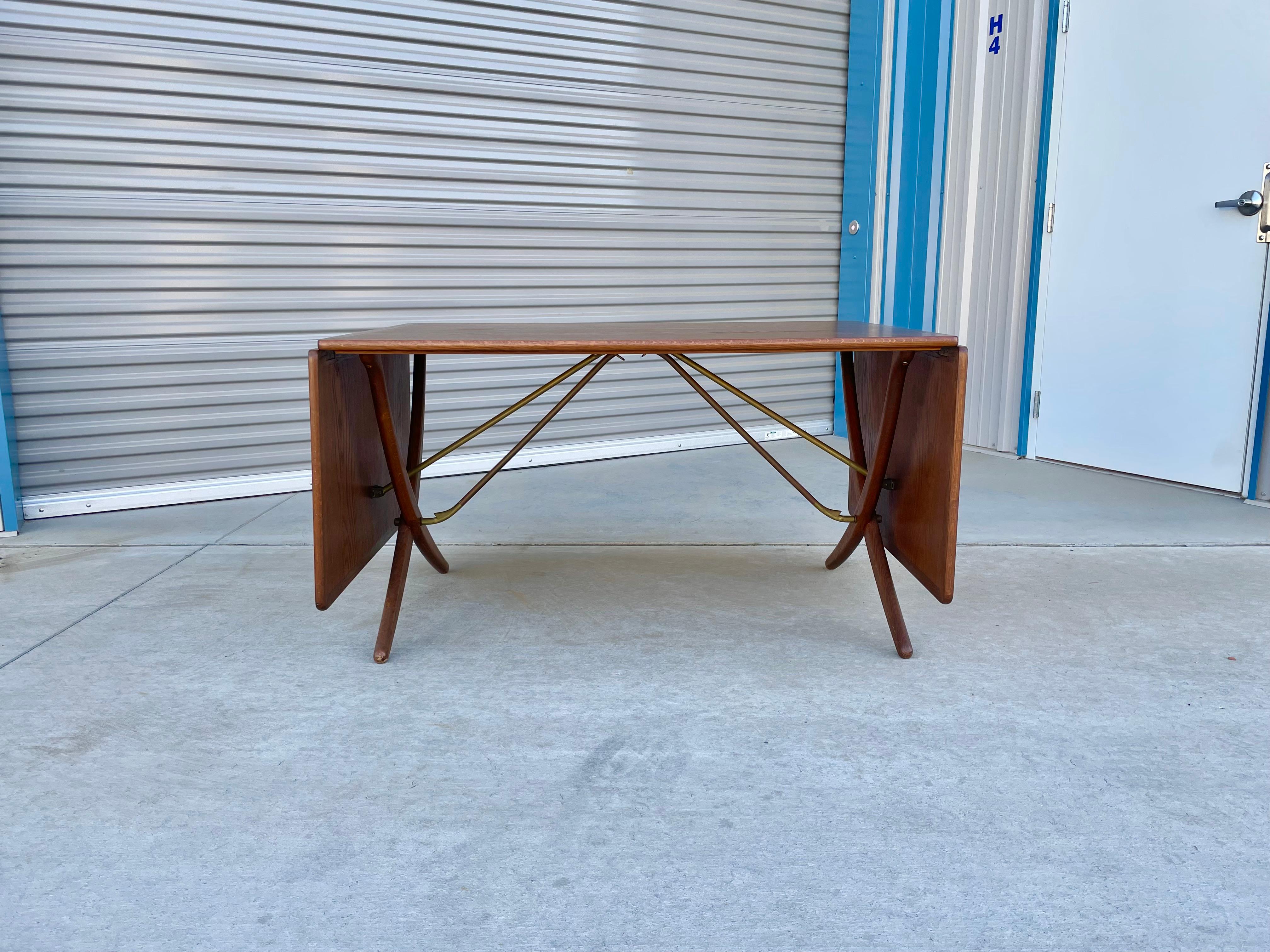 Dänischer Esstisch mit Säbelbeinen, entworfen von Hans J. Wegner für Andreas Tuck in Dänemark im Jahr 1950. Dieser ikonische Tisch AT-304 besteht aus einer Teakholzplatte mit zwei ausklappbaren Blättern. Die architektonischen, gekreuzten Säbelbeine