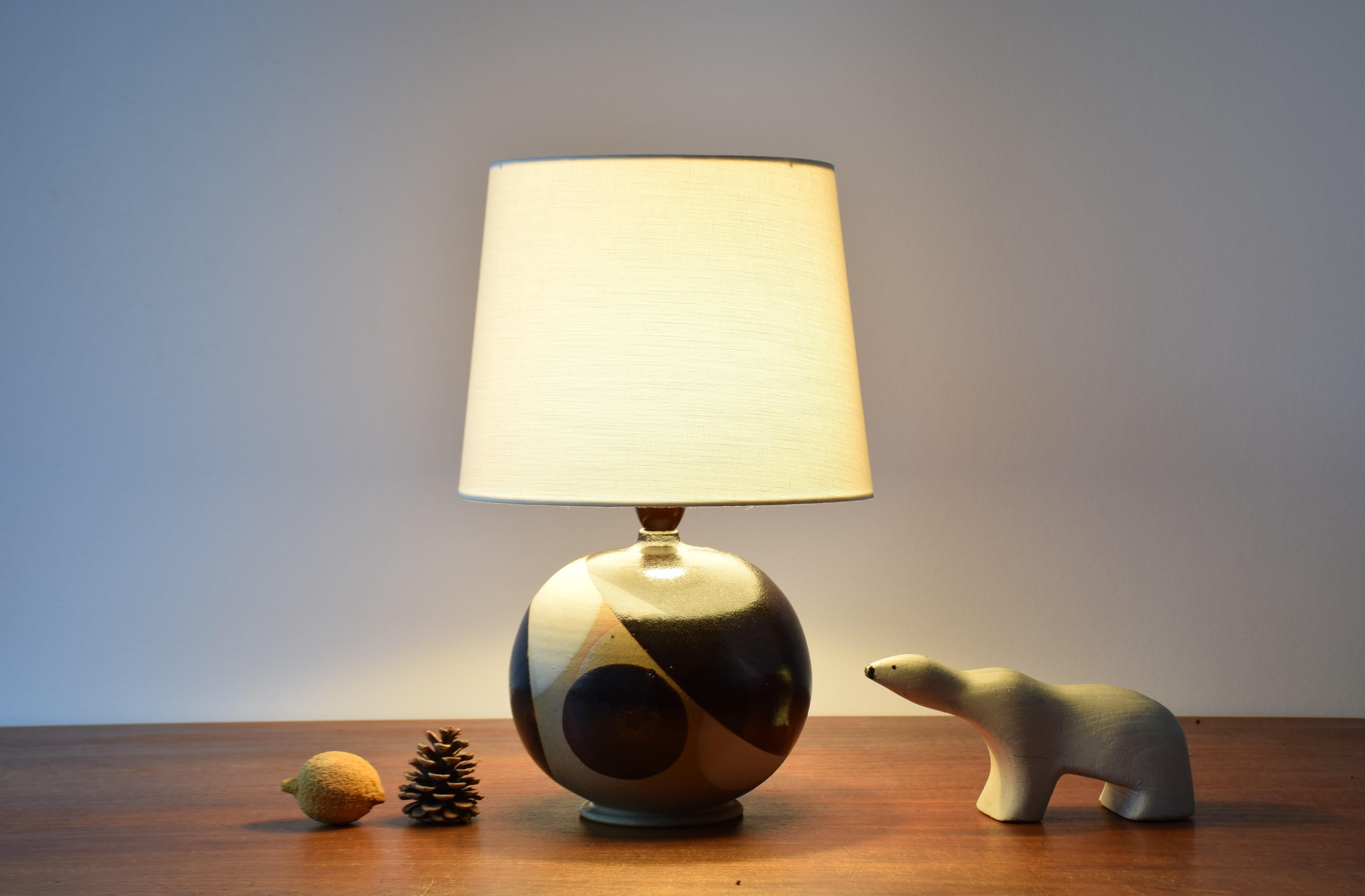 Danish Modern ball shaped ceramic table lamp by ceramists Karin and Erling Heerwagen, made 1974. 
The shape of the lamp is echoed in the decor which shows circles and part of circles in black and white glaze on the beige colored clay. The look of