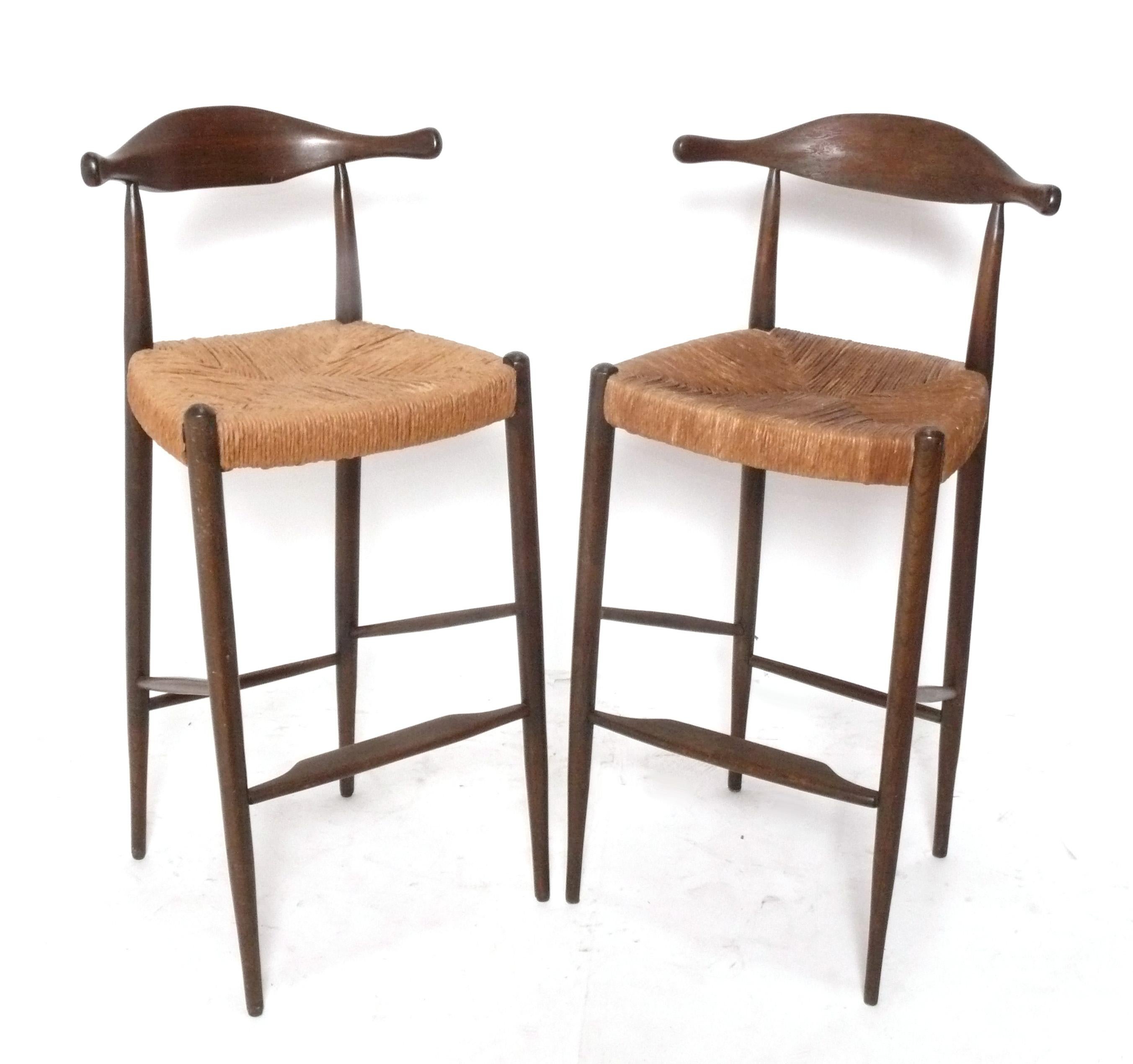 Coppia di sgabelli da bar moderni danesi, Danimarca, anni '60 circa. Sono costruite con telai in teak e sedute in giunco intrecciato. Come si vede dalle foto, i sedili presentano alcune macchie d'acqua e un sedile è leggermente più scuro dell'altro.
