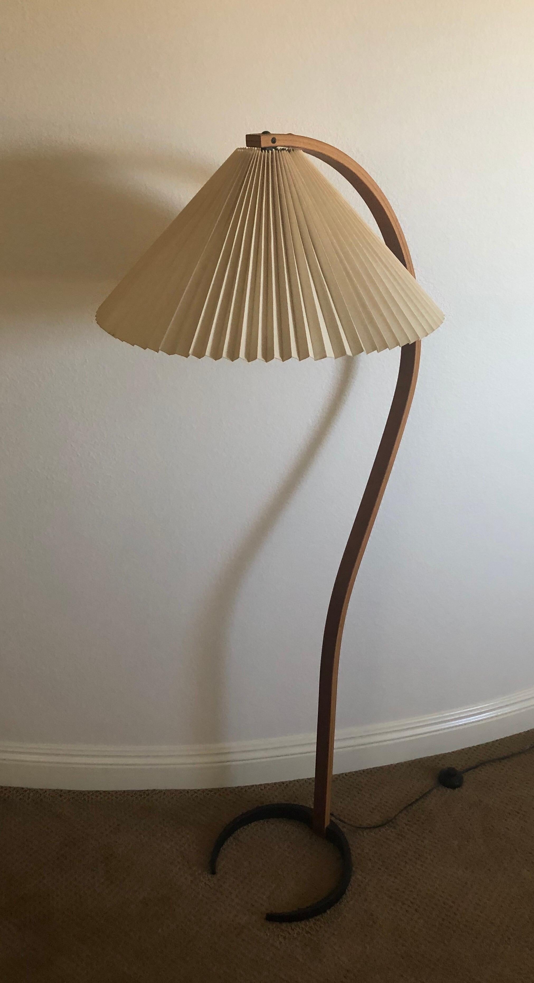 Super cool Danish modern bentwood floor lamp by Caprani Light AS., circa early 1970s.

The veneered bentwood lamp sits on a crescent black iron base and retains the original tan shade. The piece is signed on the base and in very good vintage
