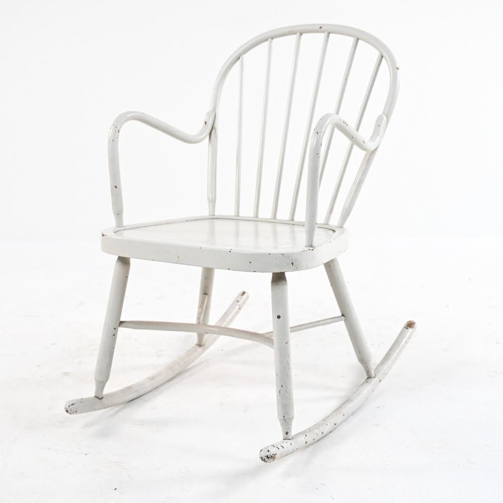 Antique and modern design meet in this Mid-Century Windsor-style rocking chair, with hoop back, graceful bentwood arms, and a modern geometric stretcher base. Finished with distressed white lacquer. In the style of Palle Suenson and Fritz Hansen.
