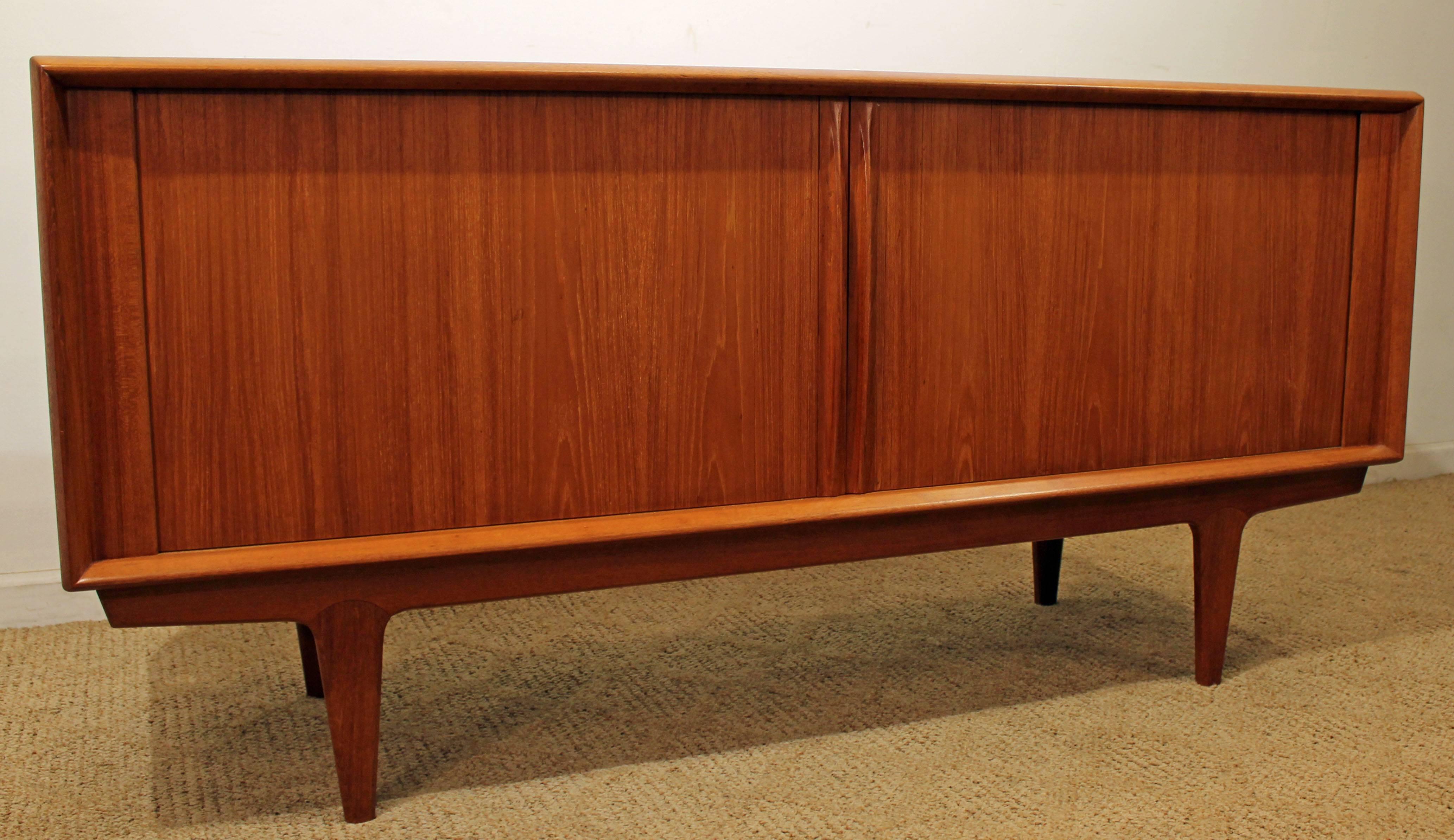 Offered is a Danish Modern teak credenza. Features tambour doors with shelving and . The piece has the look with clean lines and good organization. Features sliding tambour doors with adjustable shelving and three center drawers. It is in excellent