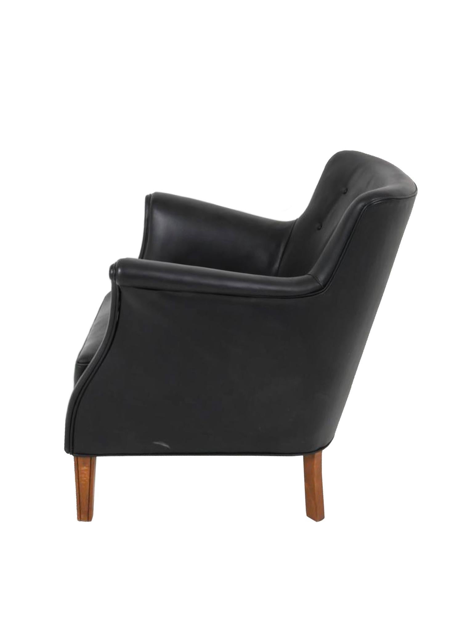 Ce fauteuil en cuir noir a été conçu par Frits Henningsen. Fabriqué dans les années 1960, il s'agit d'une version moderne danoise d'un fauteuil traditionnel, avec des lignes douces tout en conservant une forme ouverte et accueillante, propice à la
