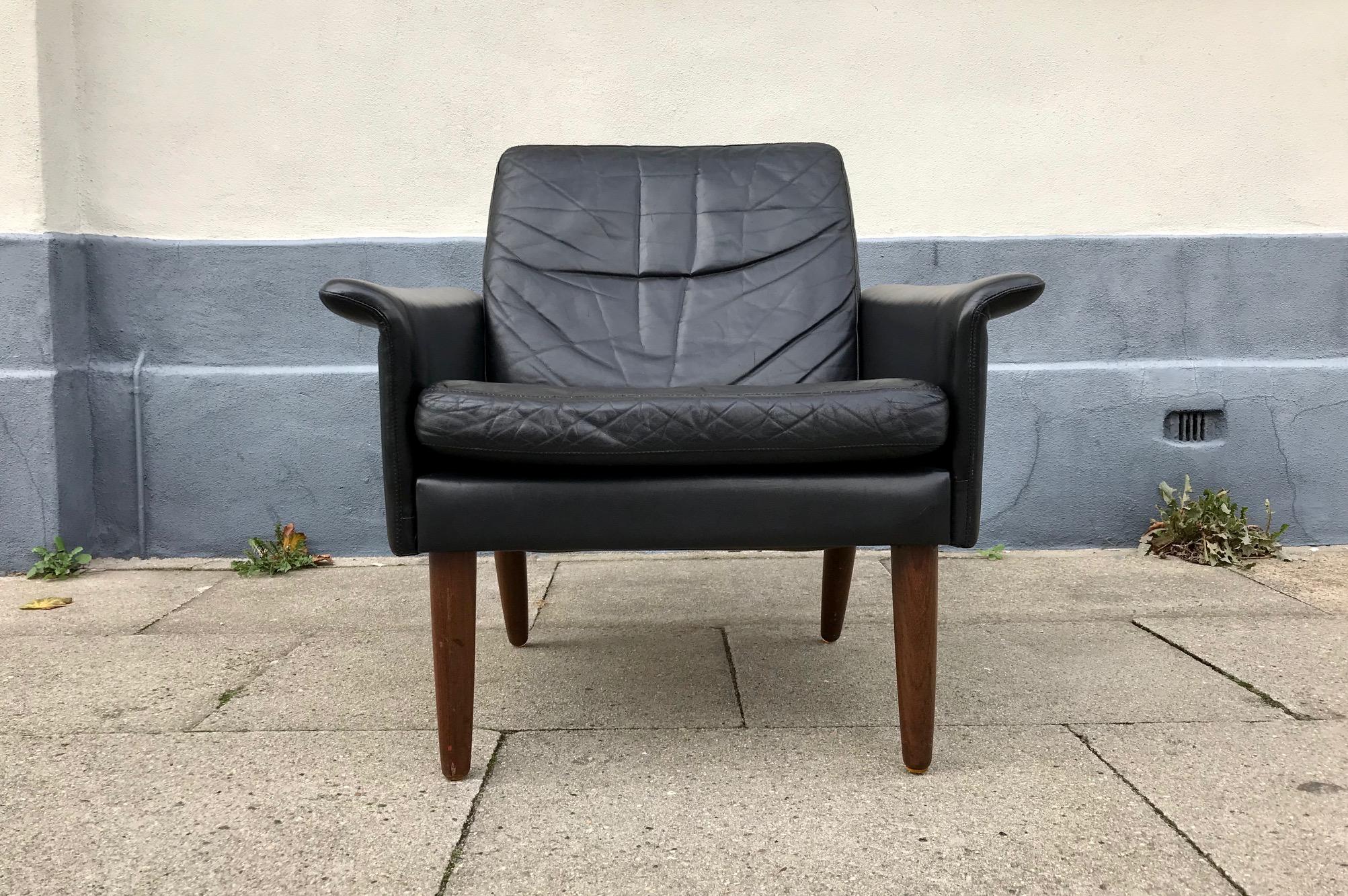 All original Hans Olsen lounge chair designed during the early 1960s and manufactured at CS Moebler in Denmark. This example is upholstered in its original soft black leather and has tapered legs in solid teak.