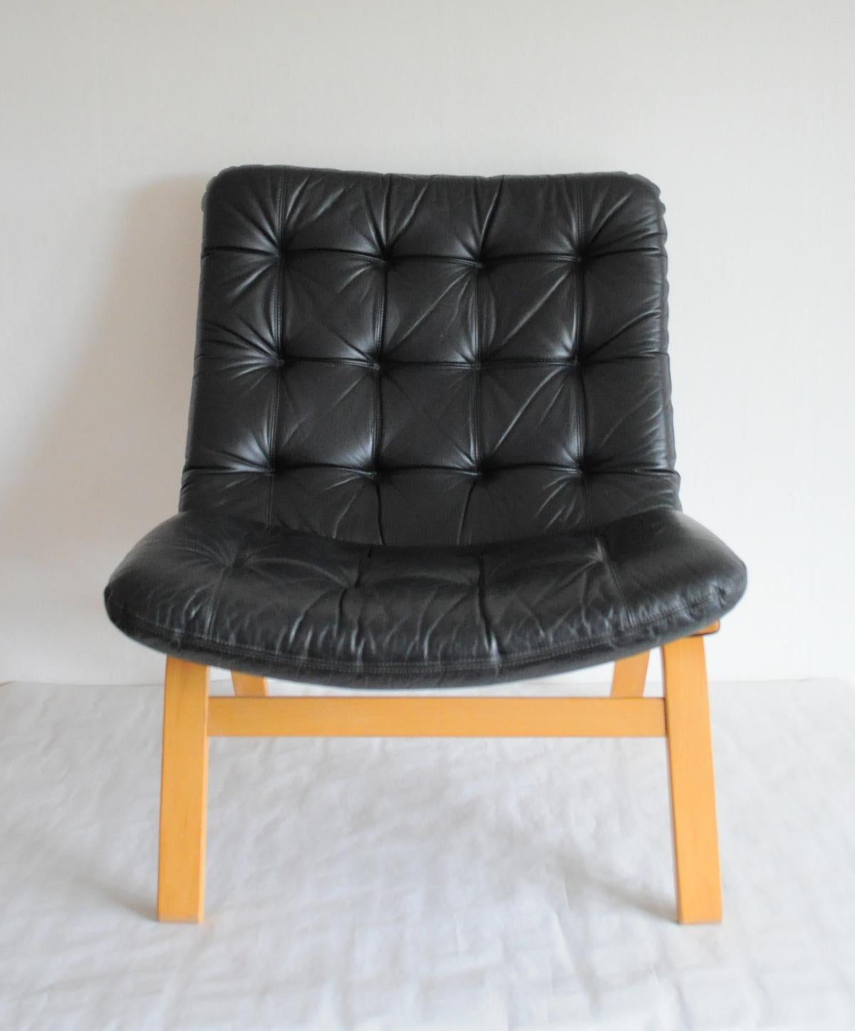 Black leather lounge chair. Leather upholstery in a fine condition. Frame in laminated beech. 
Good vintage condition. Patinated with signs of wear consistent with age and use.

Dimensions: W x D x H - 60 x 78 x 80 cm.
Seat height: 40.

Can be